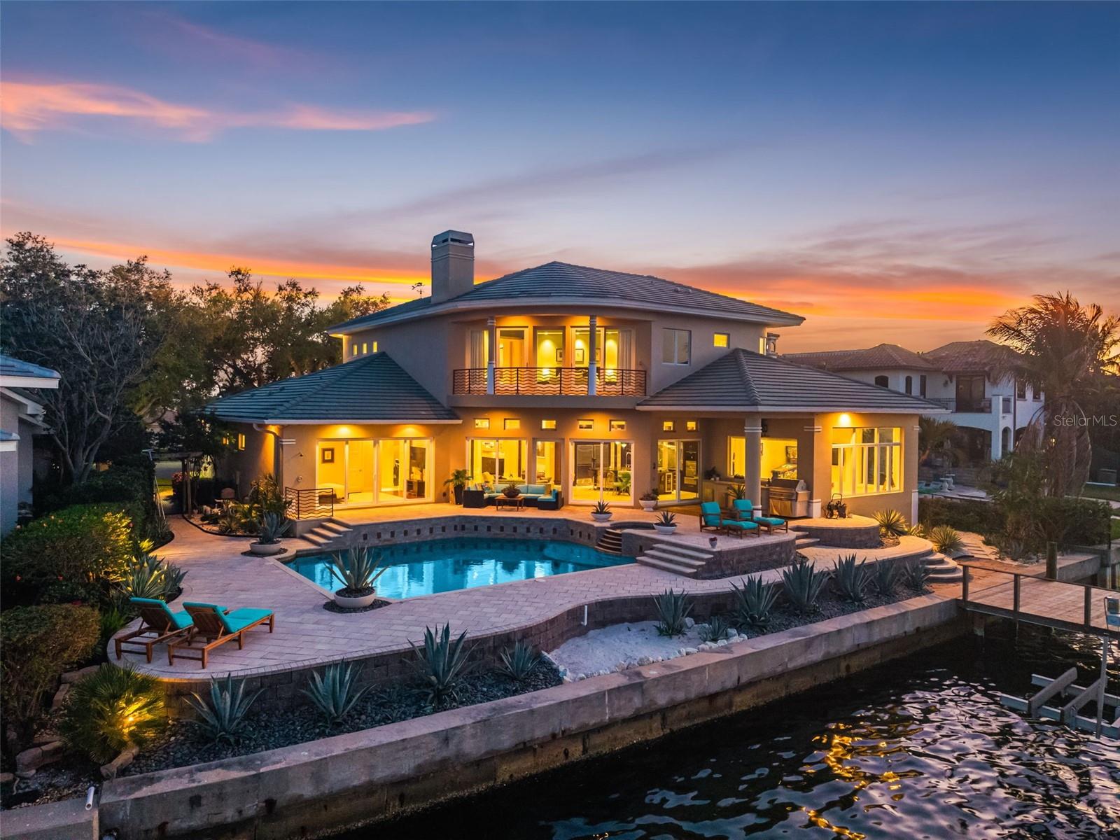 Welcome home to one of the most extraordinarily rare open waterfront opportunities in St. Petersburg. Imagine waking each morning to endless open water, the first light of sunrise glistening across Tampa Bay as dolphins quietly pass your dock and the distant skyline shimmers on the horizon. Tucked at the end of a quiet cul-de-sac on the coveted open-water side of Mermaid Point, this exceptional custom estate offers something rarely seen in today’s market. Homes on this stretch of open waterfront almost never come available, making this a true generational opportunity to own one of the most spectacular vantage points in the area. From nearly every major living space, sweeping views stretch across Tampa Bay toward the protected beauty of Weedon Island Preserve and the distant skyline of Downtown Tampa. Custom built by award-winning builder Tom Pici & Son, the home blends durability with refined modern living. Constructed with block and steel, impact-rated windows and doors, and elevated above the base flood elevation, the residence has never flooded, reflecting its thoughtful positioning and quality construction. Set along 107' of deep sailboat water, the property is ideal for boating enthusiasts. The Speeler-built dock with two boat lifts allows you to be cruising the open waters of Tampa Bay in minutes. Inside, Brazilian hardwood double doors open to a tranquil foyer highlighted by a dramatic floor-to-ceiling indoor waterfall. The homes open design and soaring 12' ceilings flood the interior with natural light while framing expansive water views. A Crestron integrated smart home system provides effortless control of lighting, climate, entertainment, and security, while motorized window treatments, recessed LED lighting, whole-house water filtration, and two Rinnai tankless water heaters enhance comfort and efficiency. The chefs kitchen is designed for gathering and entertaining, featuring custom cabinetry by Michael Bright and a Newer premium appliance suite including a Wolf gas range, Sub-Zero refrigeration, and Miele coffee station with Miele double ovens. A stunning Madagascar granite island with prep sink anchors the space, while a hidden walk-in pantry and built-in breakfast banquette connect seamlessly to the family room, where a wood-burning fireplace and breathtaking water views create a warm gathering place. The expansive primary suite serves as a private retreat overlooking the bay and skyline, complete with its own fireplace and a spa-inspired bath featuring a Pearl whirlpool tub, steam shower, floating double vanity, warming rack, Toto smart toilet and bidet, and spacious custom dressing room. Additional living spaces include a screening room with seating for eight, 3 additional en-suite bedrooms—including a wellness room and a junior suite with direct pool access—and 2 interior laundry rooms. Outdoor living is equally exceptional. A two-tier waterfront deck overlooks the open bay, while the Sekas-designed saltwater pool and spa with swim jets, sun shelf, and outdoor kitchen creates the perfect setting for entertaining or quiet evenings under the stars. While the setting feels private and serene, the location is remarkably convenient—just minutes from Downtown St. Pete, the Vinoy Golf Club, world-class dining, museums, parks, and the vibrant St. Pete Pier. 2279 Mermaid Pt recently appraised at $4.85M in 2025. This is a rare opportunity to live on one of the most extraordinary open-water settings in all of St. Petersburg.