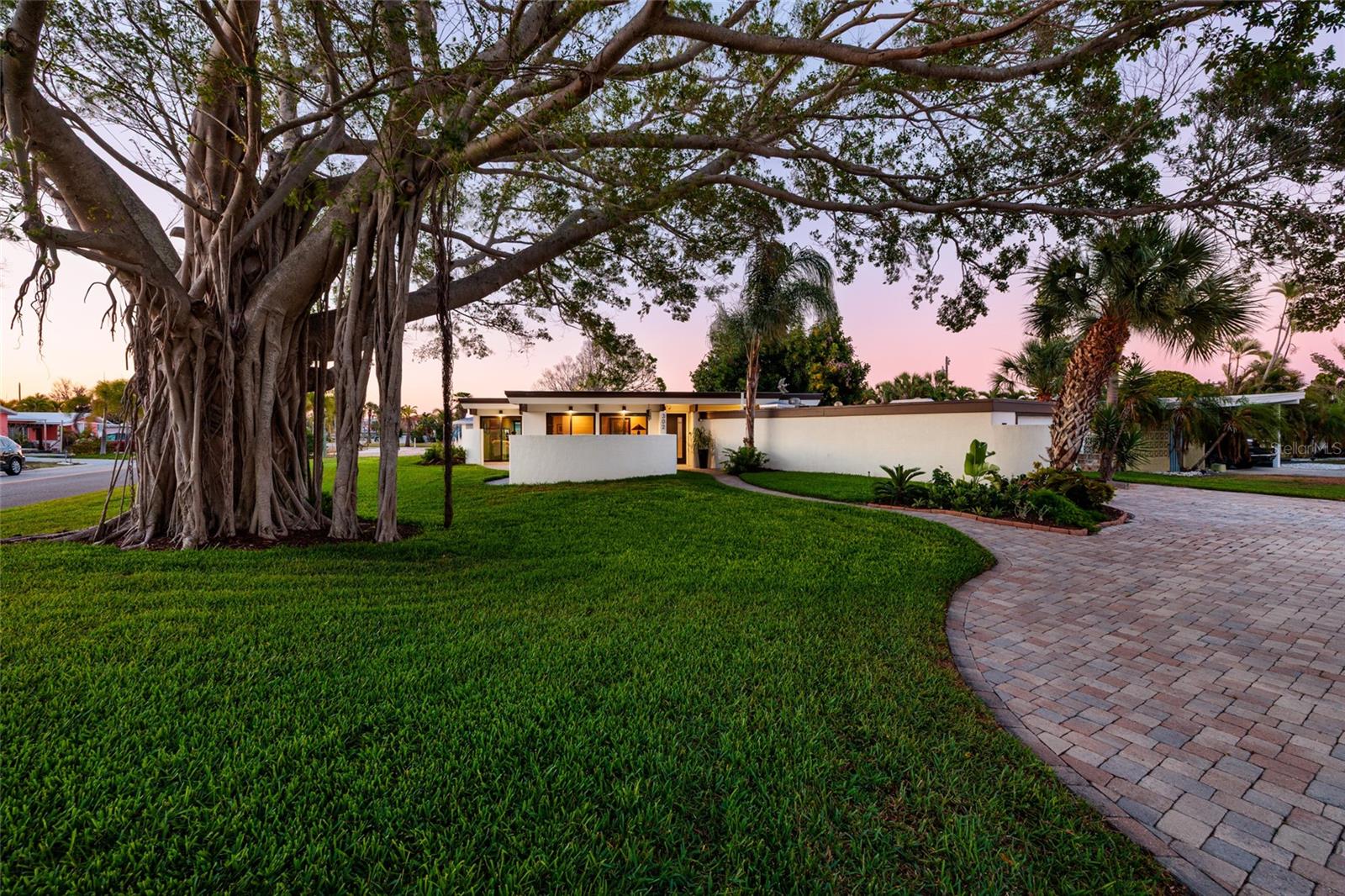 Beautifully remodeled mid-century modern home, originally built in 1973, blending timeless design with high-end upgrades located in the popular Belle Vista neighborhood on St. Pete Beach! No water intrusion in the home during Hurricane Helene (2024), as this home sits slightly elevated from the street (elevation certificate available upon request). This 2-bedroom, 2-bath home features abundant natural light through skylights and expansive sliding glass doors. Fully renovated in 2022 with new electrical, plumbing, tankless water heater, and energy-efficient mini-split systems. The sleek kitchen boasts LG stainless steel appliances and Cambria quartz countertops, with premium quartz also in the bathrooms. Hurricane-rated windows and doors, powered roller shades, custom closet systems, and dimmable recessed lighting provide modern comfort and convenience. An AC/heated one-car garage offers flexible space for a studio, workshop, or hobbies. Outdoor living on this large lot shines with mature landscaping, a circular driveway, commercial-grade roof, paver patios, a stylish pergola, and custom exterior lighting—perfect for entertaining or relaxing. Exposed beam ceilings and original 1973 blueprints highlight the home’s architectural character. Shaded by a mature banyan tree, this turnkey property combines mid-century charm, modern luxury, and an unbeatable coastal lifestyle. Located roughly 1/2 mile to the sand on St. Pete Beach, with neighborhood beach access located across Gulf Blvd! Close to many of the famous St. Pete Beach restaurants, shops, and bars. Come take a look today and live the beach lifestyle in true mid-century modern luxury!
