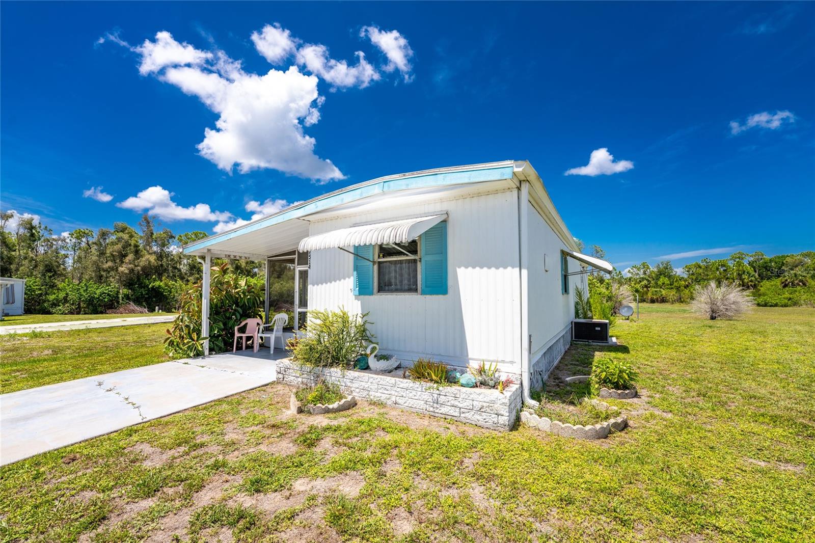 Welcome to this charming 2-bedroom, 1-bath home located in the highly desirable waterfront community of Village of Holiday Lake! This property features new subfloors and laminate top floors.

The home boasts an inviting eat-in kitchen, a spacious lanai, and a separate laundry room.. An addition to the second bedroom has transformed it into a generously sized primary bedroom measuring approximately 8' x 15'. The lanai also includes a dedicated utility room with a washer and sink, providing excellent potential for the addition of a second bathroom.

Need extra storage or workspace? You'll love the attached 100-square-foot workshop/shed, perfect for hobbies, projects, or additional storage. Step outside to enjoy the private backyard patio overlooking a peaceful greenbelt and wooded area, creating a serene setting for relaxing or entertaining.

At Village of Holiday Lake, you OWN YOUR LAND —LOW HOA FEES ONLY $150 PER MONTH! Residents enjoy an exceptional lifestyle with access to 25+ boat slips offering direct access to Charlotte Harbor and the Gulf. Amenities include TWO POOLS, BBQ area, a large recreation hall with a full kitchen, FITNESS CENTER, library, craft room, woodworking shop, pool tables, PICKLEBALL, tennis courts, shuffleboard, laundry facilities, and more.

Conveniently located near shopping, restaurants, grocery stores, gyms, nightlife, bike trails, and beautiful Gulf Coast beaches, this community truly has it all. Experience the relaxed Florida lifestyle in one of Port Charlotte's most sought-after neighborhoods, where GOLF CARTS are the preferred mode of transportation.

Don't miss your opportunity to own this adorable home—schedule your private showing today before it's gone!