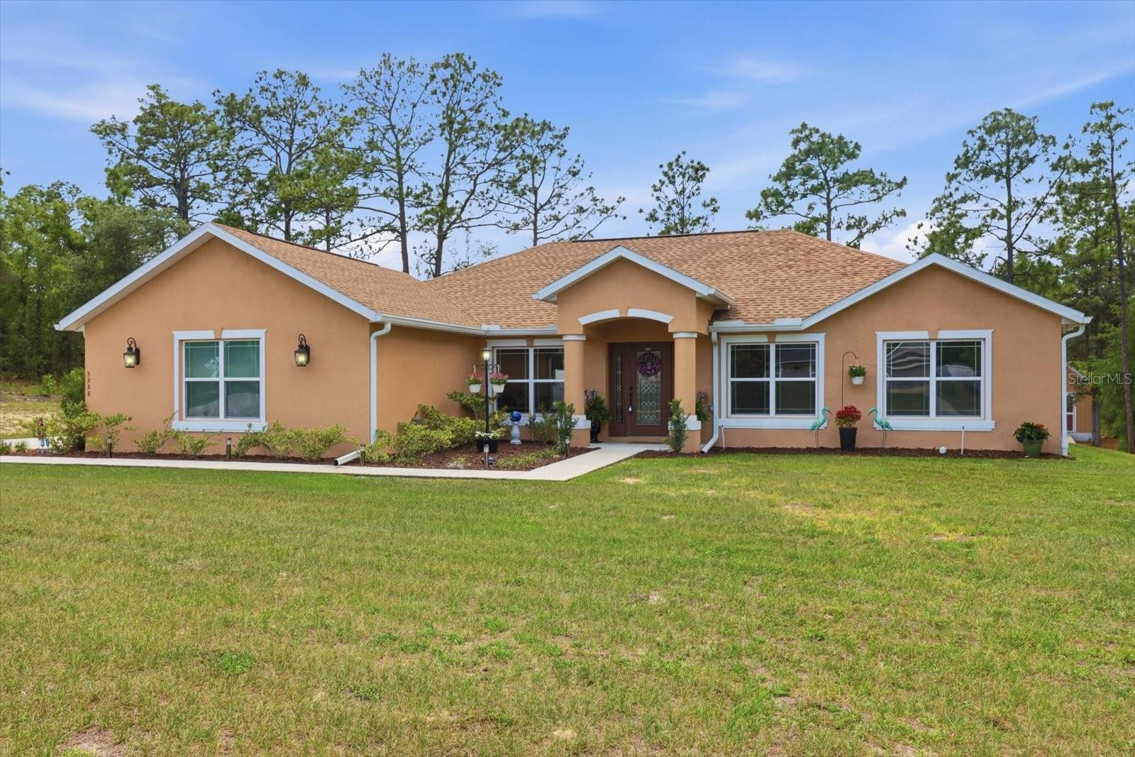 Beautiful 3-bedroom, 2-bath home built in 2022 located in the highly desirable Pine Ridge community. Situated on 1 private acre, this move-in ready home offers an open, bright, and inviting floor plan with a spacious family room and kitchen combination, separate living room/den, and formal dining room. The kitchen features a large island with sink, pantry, top appliances, and overlooks the main living area, making it perfect for entertaining. Updated lighting throughout adds a modern touch to the home’s warm and welcoming atmosphere. The spacious primary suite includes dual sinks and a stunning walk-in “snail” shower. A convenient exterior door from the primary bath provides direct access to the backyard, ideal for a future pool installation. Enjoy outdoor living from the large covered back porch overlooking the expansive property. The long driveway with additional bump-out parking offers plenty of space for guests, RVs, or extra vehicles. Located in sought-after Pine Ridge, known for its large homesites and equestrian-friendly lifestyle.