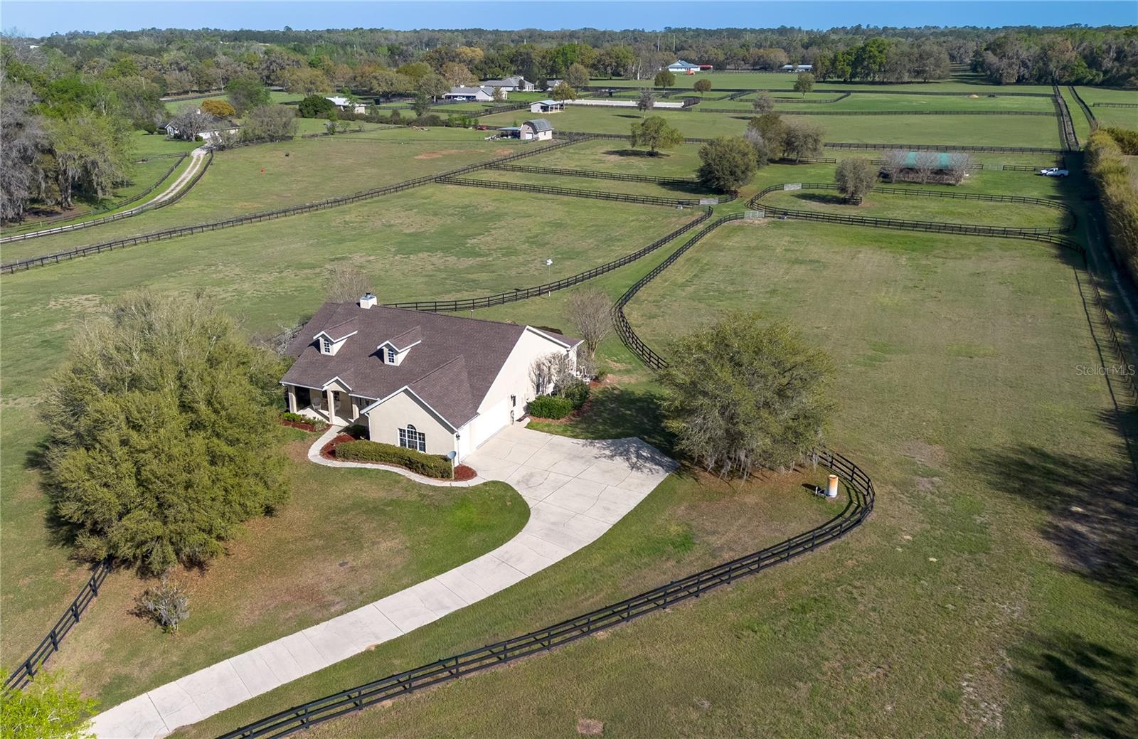 Nestled at the heart of NW Ocala’s vibrant horse country, this well-appointed horse farm is set on just over 10-acres of gently rolling land within the equestrian neighborhood of Golden Farms. Fenced and gated with two entrances along a quiet dead-end road, the property features a line of trees along the front perimeter for added privacy. Down a curved driveway towards the front of the property is the inviting 3-bedroom, 2-bath block home accented by mature landscaping, a spacious covered country-style front patio with ceiling fans, and side-entry 2.5-car garage. Inside, the home is light and bright with an open, split-bedroom floor plan, high ceilings with tray accents, and wood flooring that runs throughout the main spaces. The living room features a high-performance clean-burning wood fireplace that creates an inviting atmosphere. Those who enjoy cooking will love the well-appointed kitchen, which features abundant cabinet and counter space, stainless steel appliances, gas range, and a large breakfast bar– all positioned to flow easily into dining and living areas, ideal for both everyday living and entertaining. The split-bedroom layout ensures privacy throughout, with a spacious primary suite that includes dual walk-in closets and a private en-suite bath with a built-in vanity, garden tub, and glass-door shower. A surround-sound speaker system is in place throughout, making it easy to enjoy music or set the ambience no matter where you are in the home, with plenty of options for adding in additional speakers. Outside, the screen-enclosed patio overlooks the private infinity-edge pool and spa, designed to capture expansive views of the surrounding pasture. This outdoor space is perfectly suited for relaxing or entertaining while enjoying the peaceful setting year-round. An on-demand generator is in place to keep some of essentials powered even during sudden power outages. Equestrian amenities are thoughtfully laid out throughout the property, including an 8-stall center-aisle barn with feed room, tack room, wash rack, hot water, and a fly spray system. A separate entrance is in place for direct barn access, adding to the utility. A total of 7 paddocks are established with 3-board fencing and no-climb wire, offering flexibility for turnout and training. Ideally located just 10 minutes from the World Equestrian Center (WEC) and 13 minutes from HITS, this farm is perfect for those looking to take get the most out of some of the area’s most exciting competition venues and still be nearby a variety of tack and feed stores, equestrian service providers, and world-class veterinary care. Both Golden Ocala Golf & Equestrian Club and Golden Hills Golf Club are also just minutes away, offering additional opportunities to enjoy the year-round sunshine on world-class golf courses. This property offers a rare opportunity to enjoy space, privacy, and a well-equipped farm layout ready to support a variety of disciplines– schedule your showing today!