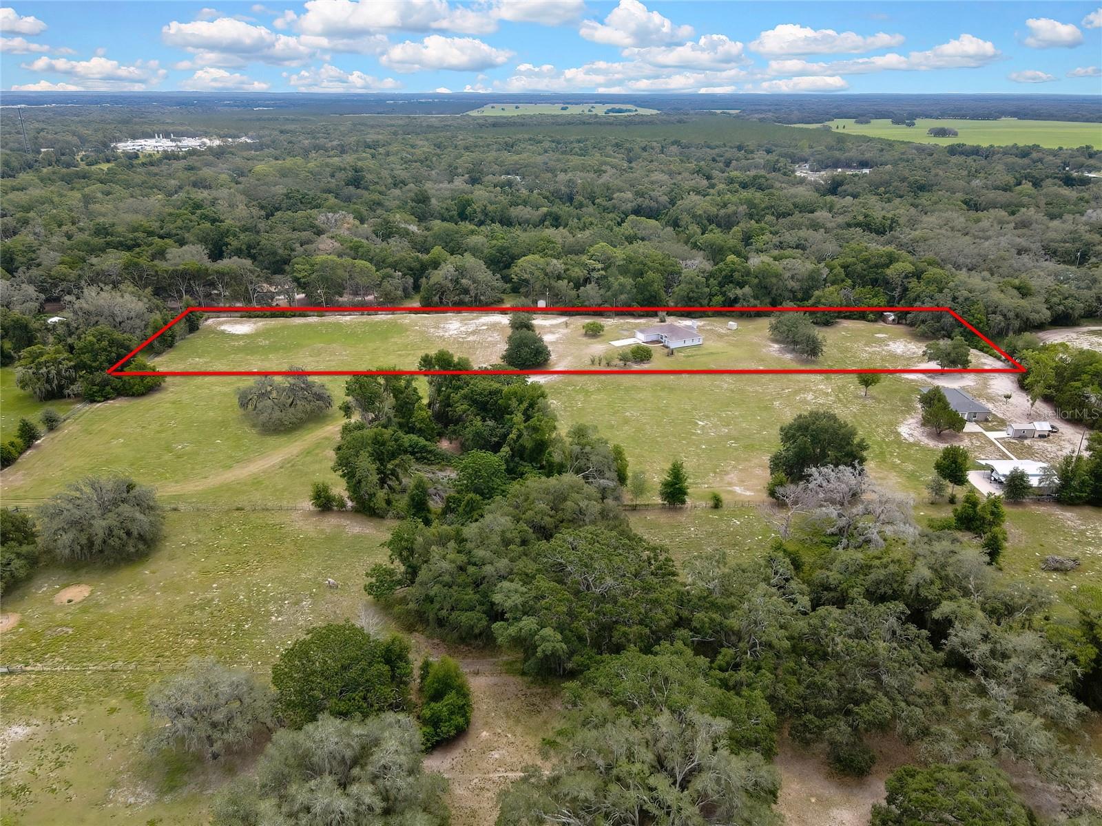 By appointment only, Please do not drive up to the property without permission. **Zoned for Land O’Lakes High School.** Set on 5.05 flat, open acres bordered by a natural canopy of mature trees, this Spring Hill property offers the kind of space, privacy, and serenity that has become genuinely rare in today's Florida market. Whether you're enjoying the peaceful surroundings at sunrise or watching the tree line glow at dusk, every moment here feels unhurried and entirely your own. Lovingly maintained by its original owner since built in 1997, this 3-bedroom+office, 2-bathroom, 2-car garage home offers 1,927 sq ft of single-story living set amid of the natural beauty of Pasco County's countryside. While the property could benefit from some tender loving care and cosmetic updates, it presents an exceptional opportunity to create your own private retreat while enjoying peace of mind that comes with many major system improvements already completed. Recent updates include exterior paint 2026, roof 2023, A/C 2021 and professionally serviced every six months, water heater 2021, drain field 2019, and a pressure tank 2016. The property is serviced by a private well approx. 183’ deep, supporting the self-sufficient lifestyle many acreage buyers seek. The living room is generously proportioned and filled with natural light, flowing into a dedicated dining room perfect for entertaining. The kitchen features abundant cabinetry and a full appliance package, with a direct sightline into the family room anchored by a wood-burning fireplace. Sliding doors open to the rear enclosed patio, which has been thoughtfully divided into two separate spaces. One portion remains a relaxing patio area, while the other has been converted into a private office directly accessible from the primary bedroom—ideal for remote work, hobbies, a reading room, fitness space, or a quiet retreat. Beyond the patio, you'll enjoy a front-row seat to more than five acres of flat, private land—no neighbors crowding your view, just open green space, birdsong, and room to breathe. Ideal for anyone envisioning a pool, a garden, a workshop, animals, or simply wide-open space to call their own. The primary suite comfortably accommodates a sitting area alongside bedroom furnishings and includes both a walk-in closet and a secondary closet, plus an ensuite bath. The adjoining office space offers exceptional flexibility and convenience. Two additional well-sized bedrooms in a split floor plan share a full hall bath. A separate laundry room with washer and dryer keeps household operations tidy and organized. Spring Hill delivers the best of both worlds: the quiet and space of rural Florida living with access to everything you need. Situated 40 miles north of Tampa and easily accessible via the Suncoast Parkway and US-41. Five-acre parcel, functional floor plan, significant system updates, and natural privacy don't come to market often—and when they do, they don't stay long. If you've been waiting for land, space, and property that truly lets you exhale while offering the opportunity to add your own vision, this is it. Seller has never experienced flooding anywhere on the property, including during Hurricane Milton in 2024. The seller pays $350/year for flood insurance. ***Google Maps will direct you to the wrong driveway. You must turn at the mailbox where the real estate sign is located.***