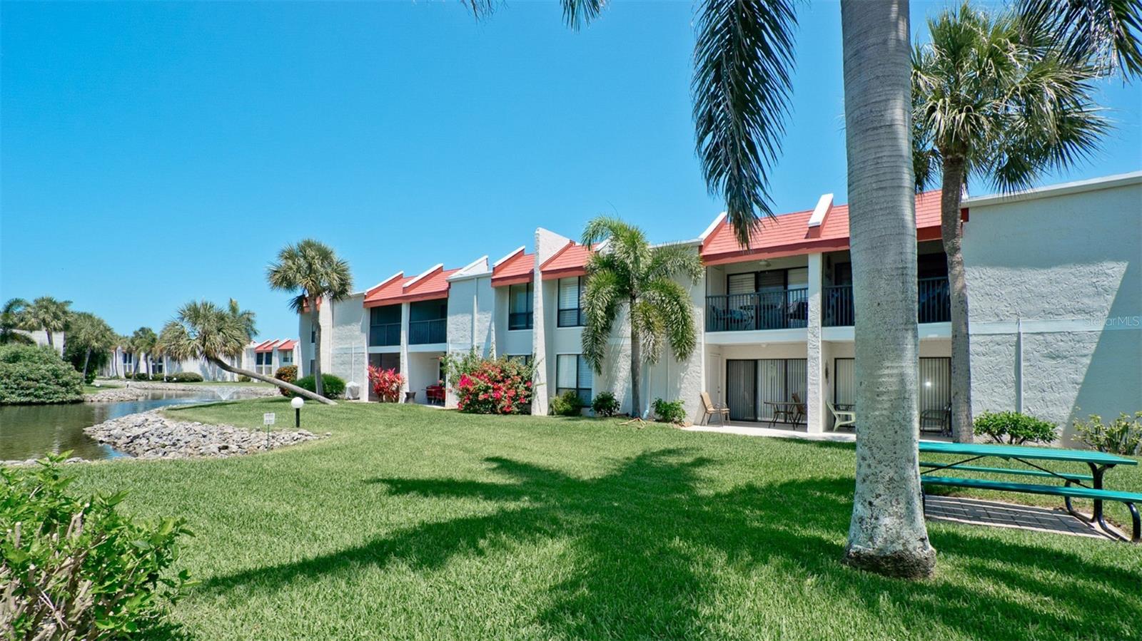 Coastal Chic Meets Bayfront Serenity
This is the one you've been waiting for. Nestled in the premier Runaway Bay community, this stunning 2BR/2BA ground-floor unit has been masterfully reimagined with a fresh, coastal-modern aesthetic that feels like a high-end boutique retreat. Fully turnkey and meticulously maintained, this home offers the rare trifecta of pond, fountain, and partial bay views right from your doorstep.

The Modern Makeover: No detail was spared in this top-to-bottom renovation (2024-2025). From the moment you walk in, the space feels bright, airy, and effortlessly cool. Gourmet Kitchen: Sleek white shaker cabinetry, premium quartz countertops, a deep farmhouse-style sink, and a high-end stainless steel appliance package (including a French door fridge). Designer Flooring: Beautiful luxury vinyl plank flooring flows throughout the living areas, offering durability without sacrificing style. Spa-Like Baths: Both bathrooms are fully modernized with custom tile work, walk-in glass showers, and contemporary black hardware. Infrastructure & Peace of Mind: Rest easy with a brand-new HVAC system and water heater. Outdoor Living & Island Life - Step out onto your private patio to watch the fountain dance on the lake or the Sea birds land on the bay. Alternatively, take a short stroll to the community's private fishing dock to catch the sunrise over Sarasota Bay. Beach Access: Enjoy two private, deeded beach access points - white sands and turquoise Gulf waters are just steps away. Award-Winning Amenities: Runaway Bay is home to the largest saltwater heated pool on Anna Maria Island, plus a recently renovated clubhouse, a fitness center, tennis and pickleball courts, shuffleboard, and a kayak launch. Turnkey Ready: Whether you're looking for a personal sanctuary, a seasonal getaway, or a high-performing investment (thanks to the 7-day minimum rental policy), this unit is truly "plug and play." With a professional furniture package included, the only thing missing is your suitcase. Don't miss this opportunity to own a piece of paradise in one of the island's most amenity-rich communities.