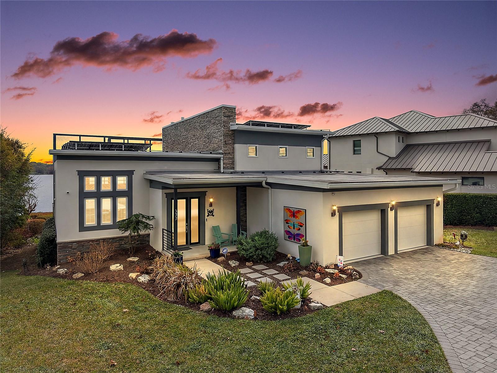 Indulge in the rare privilege of true lakefront luxury on the coveted shores of Lake Gertrude—where refined architecture, cutting-edge efficiency, and breathtaking panoramas converge in one extraordinary custom estate. Designed for the discerning buyer, this contemporary masterpiece showcases an innovative open-concept design, framed by disappearing glass walls that effortlessly blend indoor and outdoor living. The expansive screened terrace—complete with a summer kitchen, tongue-and-groove ceiling, and statement chandelier—becomes a private waterfront lounge suspended above shimmering waters. Host unforgettable evenings beneath painted sunsets and starlit skies as boats glide quietly across the lake. Inside, polished concrete floors, soaring ceilings, and a dramatic stacked-stone feature wall create a striking yet sophisticated ambiance. A sleek gas fireplace anchors the grand living space, while the chef’s kitchen rivals those found in luxury design magazines—Quartz surfaces, custom European-style cabinetry, premium stainless steel appliances, an oversized waterfall island, and a JennAir gas range deliver both beauty and performance. The main-level owner’s retreat is a sanctuary of tranquility and refinement. Wake each morning to uninterrupted lake views from your private sitting area. The spa-caliber bath exudes understated opulence with Quartz vanities, dual sinks, porcelain tile, and a frameless glass shower designed for indulgent relaxation. Upstairs, two private guest suites—each with its own en-suite bath and walk-in closet—offer elevated comfort. One features a secluded balcony overlooking the water, an intimate vantage point for sunrise reflections across the lake. This residence also embraces modern sustainability with solar power, ensuring exceptional efficiency without compromising luxury. Beyond the interiors, manicured grounds roll gently to a reinforced aluminum seawall and private dock—your gateway to boating and water skiing on the pristine waters of Lake Gertrude. Moments from the boutiques, fine dining, and cultural charm of downtown Mount Dora, yet worlds away in privacy and prestige, this is more than a home—it is a statement. For those who expect nothing less than exceptional, welcome to your private lakeside legacy.