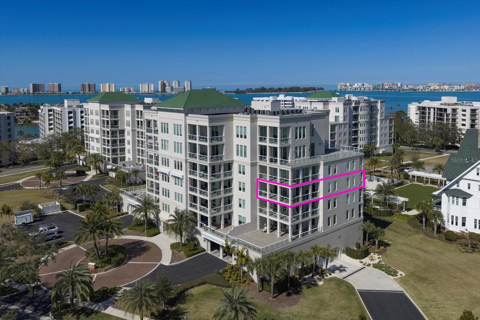 Experience refined luxury living in this stunning fourth-floor residence in the prestigious Allamanda building, tucked behind the 24-hour guarded gates of the Belleair Country Club. A former model home, this exceptional condo was designed with the most discerning buyer in mind, showcasing impeccable craftsmanship, designer finishes, and elegant neutral tones throughout. From the moment you enter the foyer, highlighted by inlaid wood floor detail and custom trim, soaring ceilings and expansive windows create a bright, open ambiance. Rich wood floors flow throughout the home, adding warmth and continuity. The living spaces are thoughtfully oriented to capture breathtaking views of the Belleair Country Club’s spectacular golf course, with two walls of sliders leading to an expansive wraparound terrace that seamlessly blends indoor and outdoor living. The gourmet kitchen is both sophisticated and functional, featuring stainless steel appliances, a gas cooktop, quartz countertops, and a large island perfect for gathering and entertaining. Custom built-ins and a wine rack enhance the adjoining dining area, creating a stylish yet welcoming space for hosting. The spacious primary suite is a private retreat, complete with custom woodwork, a generous walk-in closet with built-ins and center island. The spa-inspired ensuite bath features dual vanities, elegant custom tile, and a large walk-in shower. A split-bedroom layout ensures privacy for guests or flexibility for a home office. Additional highlights include custom tile work, a large laundry room with sink, an oversized linen and storage closet, secure building access, and a 2 car garage. Move-in ready and beautifully appointed, this extraordinary Belleair residence offers elevated living in one of the area’s most exclusive communities. Reference builder's floor plan for square footage figures.