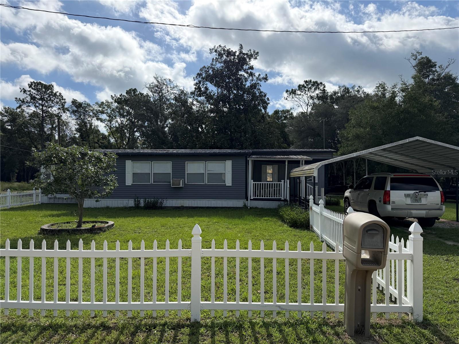 NO HOA! Nearly 1/2 acre in Rainbow Park in West Ocala with a spacious 2 bedroom, 2 bathroom manufactured home. A welcoming picket fence surrounds the front yard. There is a spacious covered front porch. Inside, the open layout offers plenty of living space open to the kitchen with oak cabinetry and a full suite of appliances. The split bedroom layout offers one bedroom with ensuite full bathroom and additional bedroom with adjacent full bathroom and laundry room. There is a covered back deck overlooking the property. The front offers a two car carport and there is an additional 2 car carport in the back and covered rv/boat parking. HVAC is 2016. CASH ONLY!