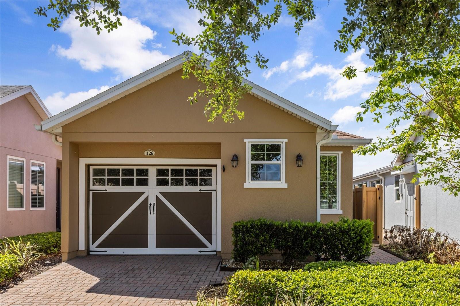 Welcome to an exceptional 2 bedroom, 2 bathroom residence within the prestigious, guard-gated community of Trilogy, where refined living meets resort-style elegance. Perfectly positioned on a premium homesite overlooking the tranquil waters of Schoolhouse Lake, this meticulously maintained home offers a rare blend of sophistication, privacy, and modern efficiency.

From the moment you arrive, you’re greeted by lush, professionally curated landscaping, tree-lined streets, and an inviting streetscape that sets the tone for the lifestyle within. Inside, a thoughtfully designed open-concept floor plan unfolds with effortless flow, ideal for both intimate living and elegant entertaining.

At the heart of the home, the upgraded chef’s kitchen showcases granite countertops, solid wood cabinetry, a central island, and a full suite of appliances—perfectly blending style and functionality. The spacious primary suite serves as a private retreat, featuring a spa-inspired ensuite bath with dual vanities, a walk-in shower with built-in bench, a private water closet, and an expansive walk-in closet. A state-of-the-art walk-in tub further enhances comfort and accessibility.

Step outside to your own private sanctuary—an exquisitely designed outdoor living space complete with extensive hardscaping, a screened and covered lanai, and electronic SunSetter shades equipped with wind sensors for effortless convenience. Enjoy breathtaking, unobstructed lake views with no rear neighbors, all within a fully fenced setting ideal for both privacy and pets.

This residence is as efficient as it is beautiful, featuring a fully paid-off Tesla solar system, natural gas, and dual-pane Low-E windows for optimal energy performance. A two-car tandem garage offers additional flexibility for storage, hobbies, or workspace.

Living in Trilogy means embracing a lifestyle unlike any other. Residents enjoy maintenance-free living with included high-speed internet, cable, security monitoring, and full lawn care. At the center of the community is the magnificent 57,000-square-foot Magnolia House—a vibrant social hub offering a private restaurant and bar with live entertainment, resort-style indoor and outdoor pools, a state-of-the-art fitness center, and an array of amenities including tennis, pickleball, bocce, billiards, and even a golf simulator. Creative spaces, clubs, and a grand event center with professional staging complete the experience.

Ideally located just 45 minutes from Orlando’s world-renowned attractions, including Disney and Universal, and approximately 90 minutes from Florida’s pristine beaches and Port Canaveral, this home offers both tranquility and accessibility.

This is more than a home—it is a lifestyle defined by luxury, connection, and effortless living.

Welcome to Trilogy. Live exceptionally.