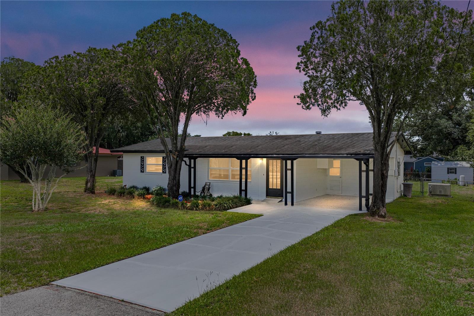Tucked onto nearly 1/3 of an acre between Dade City and Zephyrhills, this refreshed home brings together valuable updates, generous outdoor space, and a location that keeps both towns within easy reach! A newer roof, 2020 AC, double-pane windows, new luxury vinyl plank flooring, fresh interior and exterior paint, a whole house generator, and an expansive fenced backyard with a storage shed provide the next owner with peace of mind from day one.  Mature landscaping, a modern exterior paint palette, a 1 car carport, and a covered front porch create a welcoming first impression. Inside, the spacious living room feels fresh and inviting, with the kitchen and dining room just steps away. Move right in and enjoy the home as it is, or reimagine the space into an open-concept layout for maximum entertaining potential. Through a set of sliding doors, the formal living room adds warmth and character with a wood-burning fireplace and wood paneling, creating a cozy transition toward the 14x17 primary bedroom. Just off the main living areas, a full bathroom features a walk-in shower and also houses the laundry connection for added convenience. Down the hall, two additional bedrooms and a second full bathroom with a tub/shower combination provide comfortable space for additional family or guests. Head outside to a backyard that is the perfect blank slate with plenty of room to bring your ideas to life. With a large fenced yard, storage shed, and room to garden, play, and entertain- the possibilities are endless! Centrally located with quick access to Dade City, Zephyrhills, and the surrounding areas, this property brings together generous updates, expansive outdoor spaces, and a location that keeps daily life convenient. Reach out today to schedule your private tour!