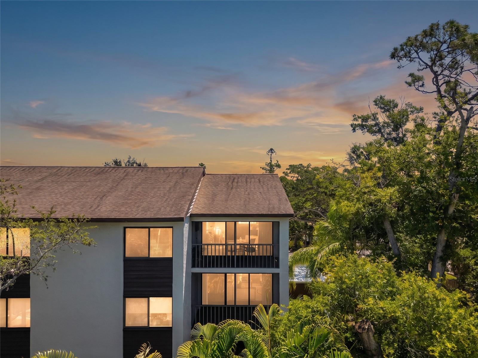 Top-floor corner unit at Orchid Oaks that comes fully furnished, turnkey, and move-in ready. This beautifully updated 2BD/2BA, 1,376 sq ft condominium is tucked beneath a canopy of mature oaks just off Phillippi Creek, offering the rare combination of natural serenity and central Sarasota convenience. The updated kitchen has been opened up and features a hood, wine fridge, and ample cabinetry. Open living and dining areas flow seamlessly to a screened lanai with electric fireplace and TV overlooking the community pool with a true treetop escape. Primary suite has a king bed, walk-in closet, and en suite bath. Guest bedroom with two twins. No carpet, only tile and LVP throughout the unit.  The in-unit laundry is right off the entry with cabinetry. One covered assigned parking space. Community has additional parking available and amenities include a pool, clubhouse, gazebo, walking trails, a dog run, plus a creekside dock. The association maintains and provides private access to the shopping center next door and the HOA dues include elevator, water, sewer, cable, pest control, roof, painting, lawn service, exterior maintenance and building insurance. 30-day minimum lease allowed up to three times per year which makes it an excellent for option for seasonal use or income production. Minutes to Siesta Key, Downtown Sarasota, SRQ Airport, golf, dining, and shopping. Relaxed Florida living at its finest.