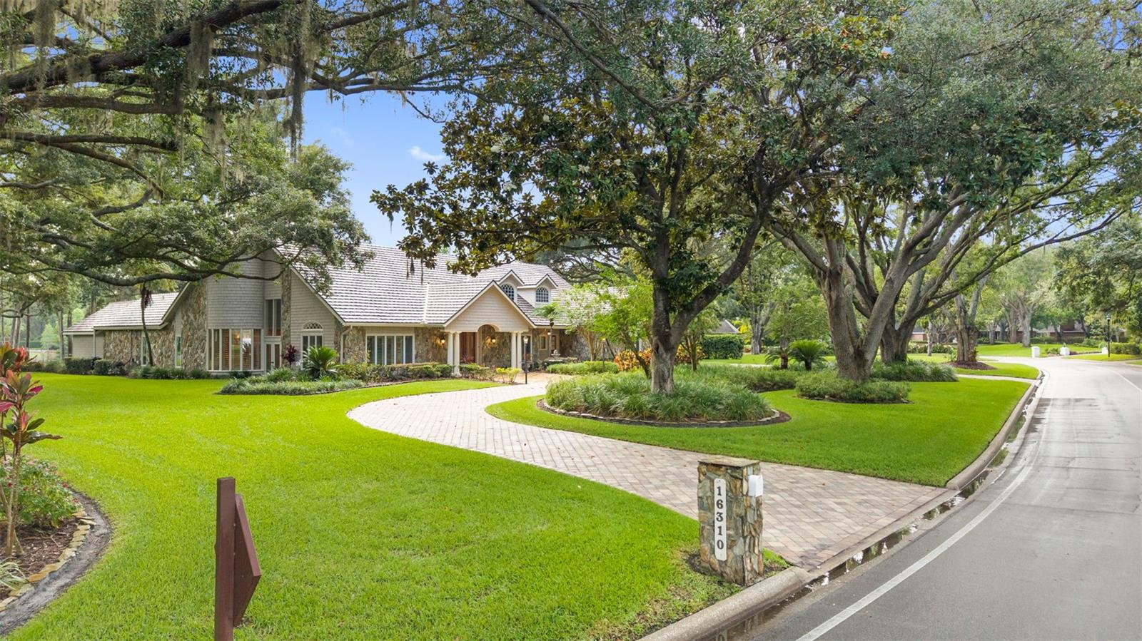 Welcome to 16310 Avila Boulevard, a rare opportunity to own one of the most exceptional single-story estate properties within Avila Golf & Country Club, Tampa Bay’s premier guard-gated luxury community.

Set on an extraordinary 1.23-acre waterfront homesite overlooking Lake Avila, this private estate offers a combination of land, water, and privacy that is seldom available within the neighborhood. While many luxury homes can be updated or reimagined over time, the setting of this property is something that simply cannot be recreated. With expansive lake views to the rear, a peaceful creek bordering the side of the property, and no rear neighbors, the homesite creates a level of privacy and tranquility rarely found in a community of this caliber.

As you arrive, a circular driveway and mature landscaping set the tone for what lies beyond. Designed around a resort-style screened PebbleTec pool and spa, the home embraces indoor-outdoor living with nearly every major living area capturing beautiful views of the water, pool, and surrounding grounds. The backyard feels like a private retreat, complete with lush gardens, a koi pond with a stone waterfall, expansive entertaining areas, an outdoor kitchen, and a setting that invites you to slow down and enjoy the beauty of the property.

Spanning 4,922 heated square feet, this thoughtfully designed estate features 5 bedrooms, 5 full bathrooms, and 2 half bathrooms, including a detached guest/pool house with its own private entrance, kitchenette, full bathroom, and walk-in shower. Whether used for guests, multigenerational living, a private office, fitness studio, or creative space, the guest house provides flexibility rarely found in today’s market.

Inside the main residence, soaring ceilings, extensive crown molding, upgraded windows and sliding glass doors, and timeless architectural details create an elegant yet comfortable living environment. The spacious primary suite offers a private retreat, while the secondary bedrooms provide exceptional comfort and privacy for family and guests.

Additional features include a metal roof, fireplace, 26KW Generac whole-house generator, 4-car garage, saltwater pool, upgraded windows and doors, and beautifully maintained grounds throughout the estate.

Residents of Avila enjoy 24-hour guarded security, roving patrol, controlled access, and optional membership opportunities at the prestigious Avila Golf & Country Club, featuring championship golf, tennis, fitness facilities, fine dining, and a premier country club lifestyle.

In a community known for luxury estates, it is rare to find a property that offers this much land, this much privacy, and such a remarkable waterfront setting. 16310 Avila Boulevard is more than a home it is one of Avila’s most unique and irreplaceable estate opportunities.