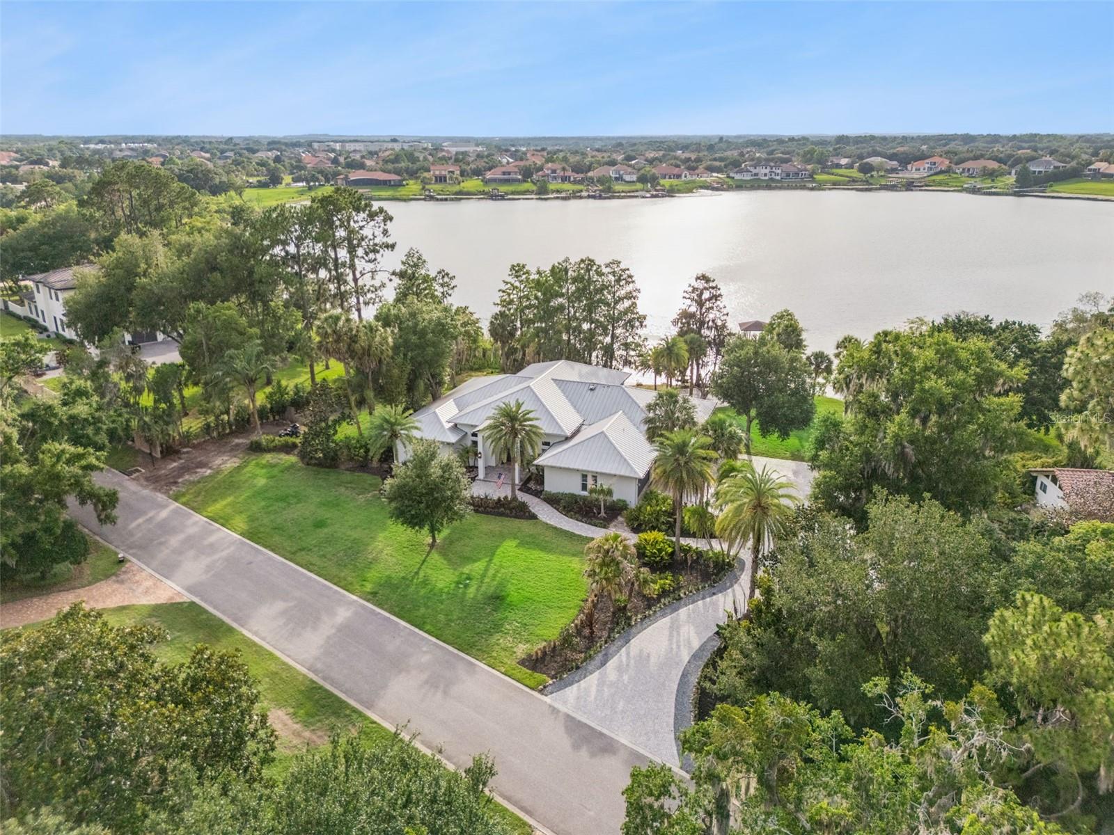 Opportunities like this in Windermere rarely reach the open market and are often treasured for generations.Welcome to an extraordinary lakefront estate in the highly coveted community of Kelso on Lake Butler, where timeless architecture, unmatched privacy and the ultimate Florida lifestyle come together on over 2 pristine acres along the shores of private Lake Davis.
This sprawling custom one-story estate offers almost 4000 square feet of thoughtfully designed living space with breathtaking sunset views, a private sandy shoreline,private boat ramp and covered boat dock on Lake Davis. Residents of Kelso on Lake Butler also enjoy exclusive access to a private community boat ramp, fishing pier and park on the world-renowned Butler Chain of Lakes,connecting you to 13 interconnected ski lakes and more than 5,000 acres of recreational paradise just moments from your front door.
From the moment you arrive, the heavily landscaped grounds,massive brick paver driveway,lush tropical landscaping & mature oak trees create a commanding first impression.Oversized double entry doors open to soaring 14-foot ceilings and an incredible open-concept living space designed for both grand entertaining and everyday comfort.The impressive great room (34x25) is anchored by a dramatic wall of custom built-ins, stunning stonework and an electric fireplace that creates an incredible focal point.
The chef’s kitchen is equally spectacular,featuring an oversized gathering island,separate Sub-Zero refrigerator and freezer,custom cabinetry and a showstopping Wolf freestanding range,vented hood and pot filler.This space was designed to bring people together and will quickly become the centerpiece of every gathering.
The  owner’s retreat is a true private sanctuary , massive custom walk-in closet with additional full sized W & D, massive spa and secluded outdoor shower. On the opposite side of the home, a bonus/flex room leads to an additional ensuite bedroom and two oversized secondary bedrooms connected by a Jack and Jill bath provide exceptional privacy and flexibility for family and guests. A secondary garage exit also allows this area to easily be converted into an in law suite.
One of the home’s most captivating features is the massive pocketing glass wall that completely opens the interior to the enormous covered & screened lanai, creating a seamless indoor-outdoor living experience. Tongue & groove ceilings,a summer kitchen and panoramic lake views transform this space into the ultimate entertaining destination.Every evening feels special as you enjoy postcard-worthy sunsets over Lake Davis from the comfort of your own backyard.
Additional highlights include a climate-controlled garage,irrigation sourced directly from the lake for reduced waterbill &a durable metal roof designed for decades of drama free ownership.
Kelso on Lake Butler is one of Windermere’s most sought-after luxury lakefront communities,known for its canopy oak-lined streets,estate homes and unmatched access to the Butler Chain of Lakes.Tucked away in one of Windermere’s best-kept secrets,yet only minutes from top-rated schools, dining, shopping and major attractions,this location perfectly balances tranquility and convenience.
This is more than a home,it is a rare legacy property and a true unicorn opportunity in the Windermere luxury real estate market. Opportunities like this are few and far between.Do not miss your chance to own one of Central Florida’s most special lakefront estates.