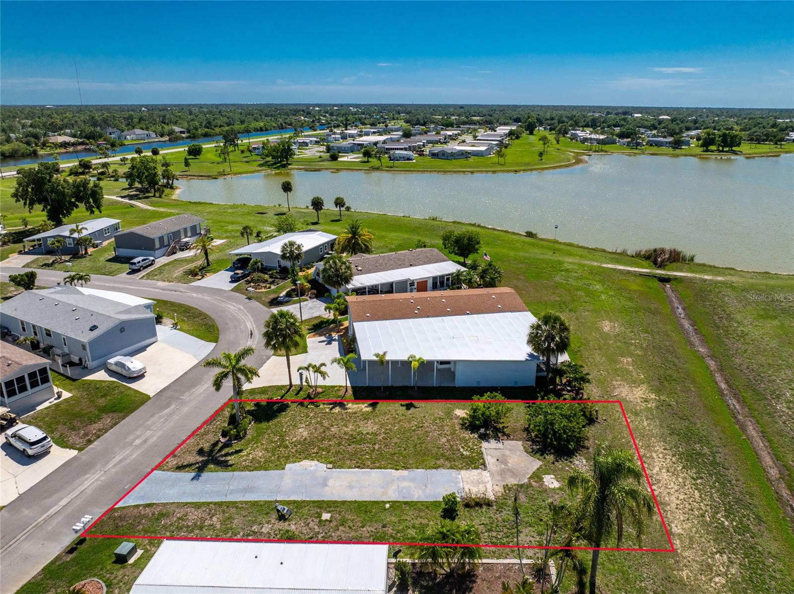 OWN YOUR OWN LAND in the highly sought-after Village of Holiday Lake, a GOLF-CART FRIENDLY, ALL-AGES WATERFRONT COMMUNITY offering the ultimate Southwest Florida lifestyle! This exceptional homesite presents a fantastic opportunity to place your dream home in a vibrant community with access to Charlotte Harbor and the Gulf. The adjacent home is also available for purchase, creating a rare opportunity for investment potential, or accommodations for family and guests. Water and electric already onsite.

Enjoy peaceful lake views from your backyard and EMBRACE THE RELAXED FLORIDA LIFESTYLE. Start your mornings with a cup of coffee overlooking the calm water, spend afternoons entertaining friends or enjoying a refreshing cocktail on the patio, and end each day with breathtaking sunsets. The tranquil setting creates the perfect backdrop for outdoor living, offering a front-row seat to colorful evening skies, native birds, and the natural beauty that makes Southwest Florida so desirable.

Residents enjoy an impressive array of amenities, including 25+ community BOAT SLIPS, a private boat ramp, TWO POOLS, a clubhouse and recreation hall with a full kitchen, FITNESS CENTER, craft room, woodworking shop, laundry facilities, tennis courts, PICKLEBALL, shuffleboard, and numerous social activities throughout the year.

Outdoor enthusiasts will appreciate easy access to boating, fishing, and NEARBY GOLF COURSES AND GULF BEACHES, while local waterfront dining favorites are just a short drive away. Conveniently located near shopping, dining, entertainment, and everyday conveniences, this property offers the perfect blend of recreation, relaxation, and value with LOW HOA FEES.

Whether you're looking for a year-round residence, seasonal retreat, or investment opportunity, this exceptional homesite offers the opportunity to create your own waterfront retreat and enjoy everything Southwest Florida has to offer. Bring your vision and start living the Florida dream!