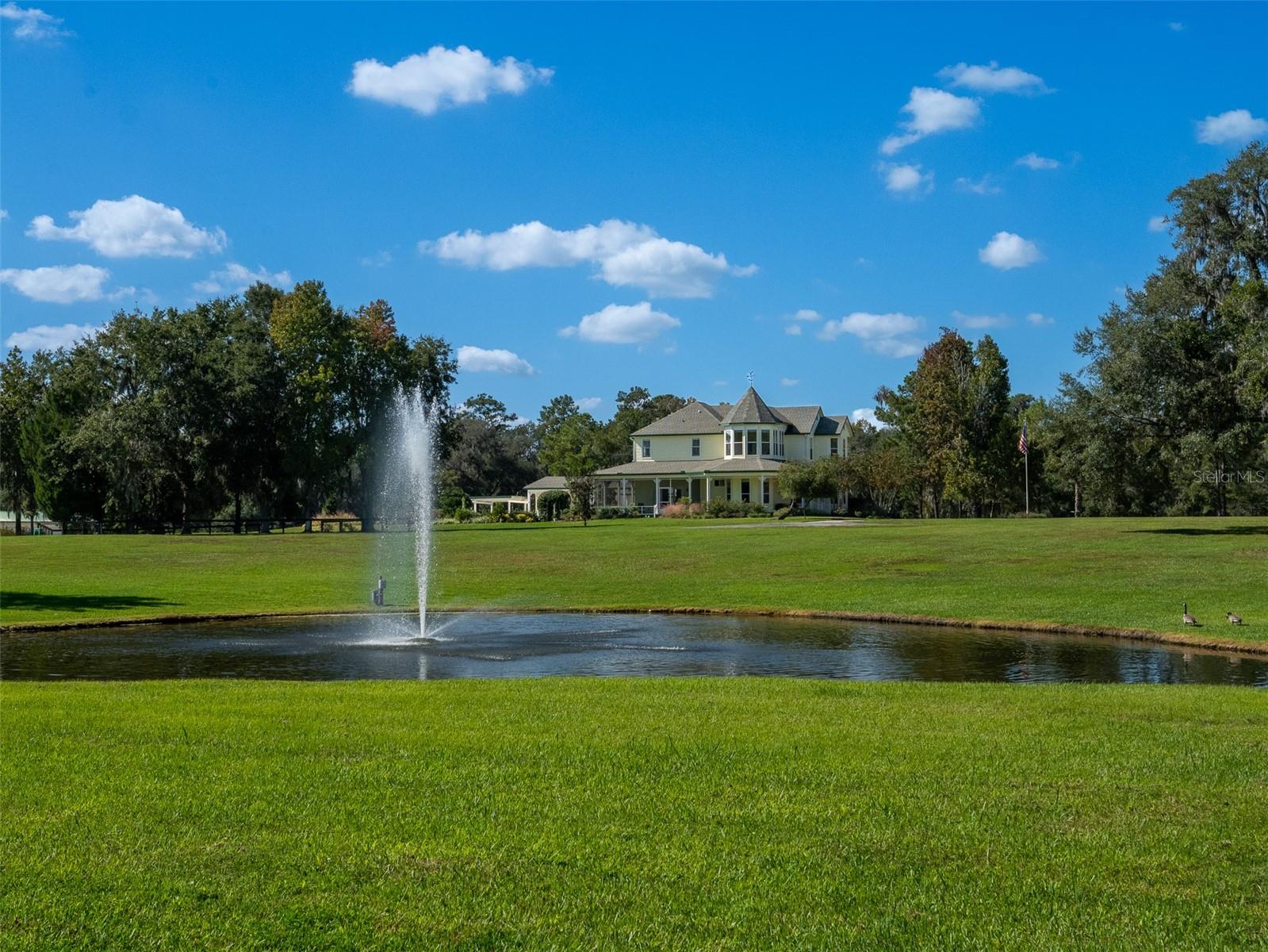 Under contract-accepting backup offers. Perfectly situated less than 10 minutes from the World Equestrian Center, this turn-key 30-acre farm in Ocala is fully fenced and thoughtfully designed with horse amenities that combine functionality and comfort. Featuring 20 lush paddocks and a center-aisle barn with 10 stalls, designed for practicality and care. The finished barn is insulated behind its beautiful tongue-and-groove ceiling, making it comfortable in every season. It also includes fans throughout for excellent ventilation, a feed room with laundry space, tack room, bathroom, wash racks with hot water, grooming areas, a fly spray system, and a water filtration system, offering every convenience for both horse and rider. Additional equestrian facilities include an arena with premium GGT footing and an irrigation system, run-in sheds, and an equipment/storage building. A pond with a beautiful fountain adds to the charm of the property’s landscaped grounds. The main residence is a two-story Victorian-style home with a welcoming wraparound porch and an attached two-car garage. Inside, you’ll find 4 bedrooms, 3 full bathrooms, a sunroom, and a cozy fireplace that enhances the home’s inviting atmosphere. The kitchen features granite countertops, solid wood cabinetry, and a walk-in pantry, offering plenty of counter and storage space. Mahogany wood flooring flows throughout much of the home, complemented by tile and carpet in select areas. Step out back and enjoy a resort-style saltwater lap pool complete with a waterfall feature, perfect for relaxing after a day at the barn. The property also includes a guest suite with a private entrance, offering 2 bedrooms, 1 bathroom, a kitchen, living area, and laundry space, ideal for guests, staff, or extended family. With its park-like setting, proximity to the World Equestrian Center, and convenient access to shopping and amenities, this property offers everything needed for both an active equestrian lifestyle and peaceful country living.