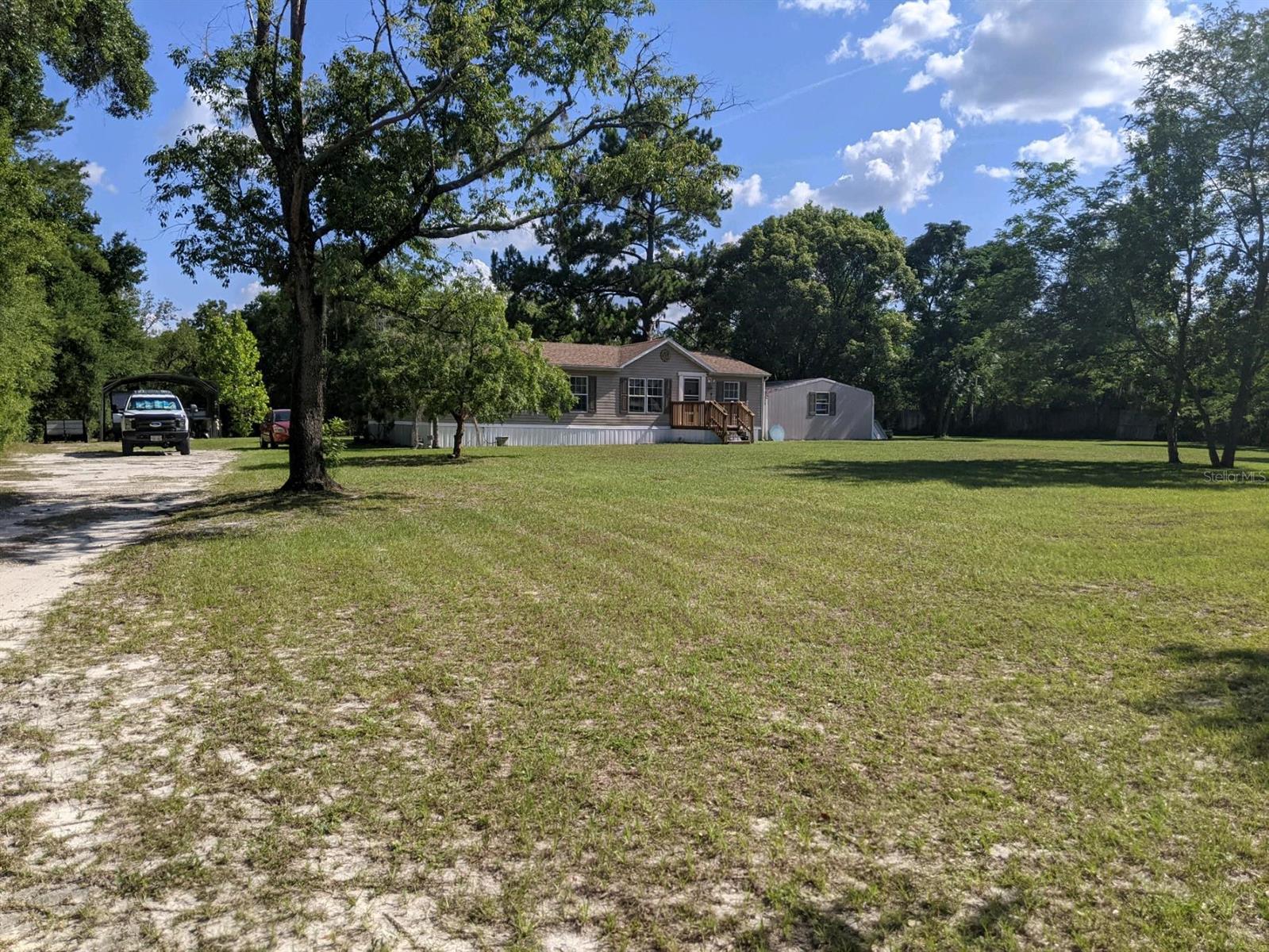 Peace and tranquility on this private 3 acre residence near The Villages, fully fenced with two gated entrances. Beautifully cared for 2001 manufactured home. New roof in 2019. Agricultural zoning makes this property perfect for horses. Three sheds, two with electric, enough room for all of your storage needs. Plenty of space for your boat and RV under the 20x31 hanger. Two areas for RV storage on site with electric. There is a 200 amp electric panel on the back end of property with a 30 amp plug. Ready for someone to build the perfect in-law suite, or barn! Water treatment system. Septic recently pumped. Fruit trees on property as well. This is a must see, don't pass this by!