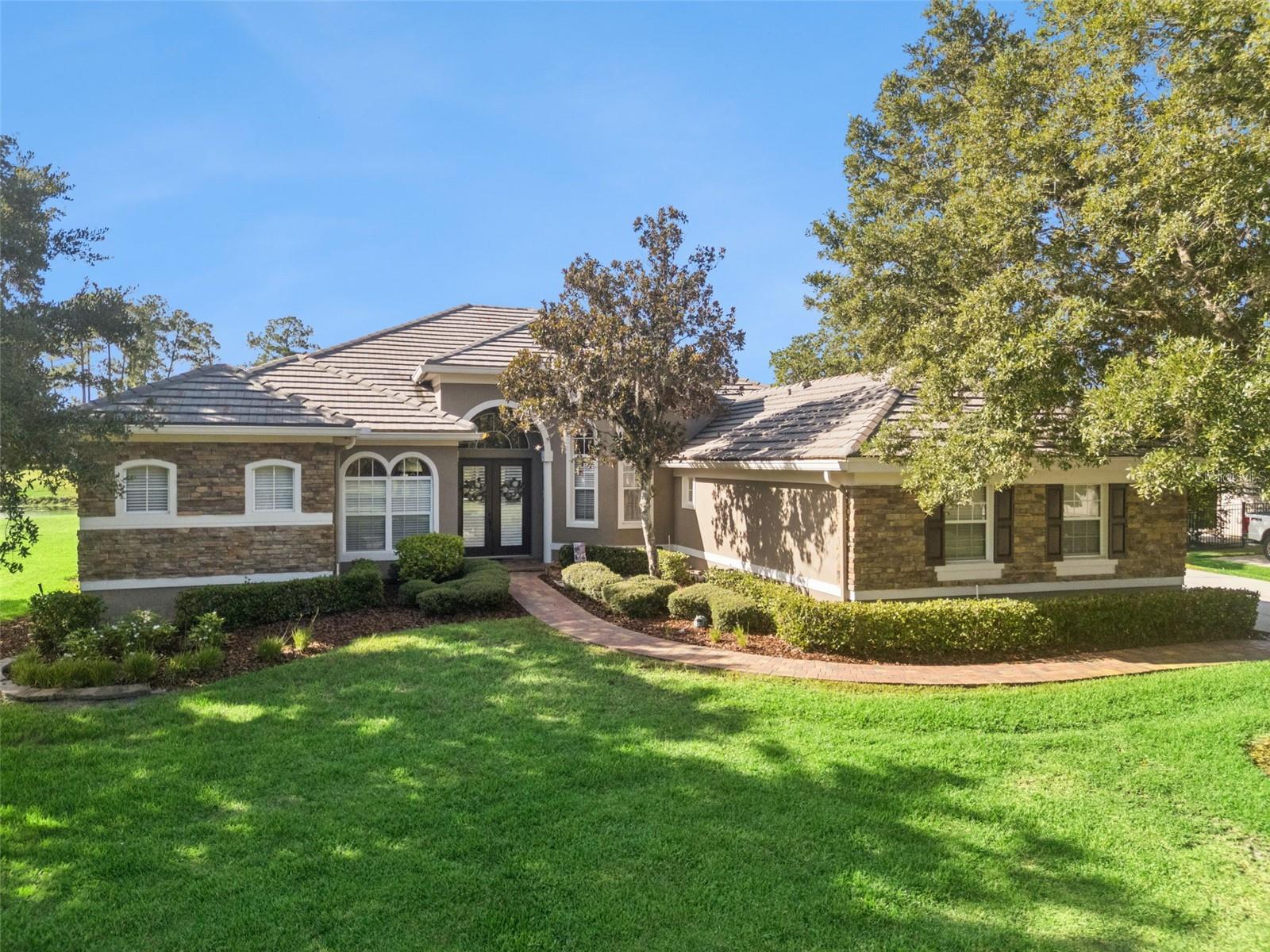 If you’re seeking a modern, open-concept layout, this beautifully designed 4-bedroom, 3-bath home delivers. Set on nearly half an acre, the property features an upgraded stone façade framed by lush landscaping and sits on a high, peninsula-style lot that enhances privacy—especially in the backyard oasis with its screened pool, spa, and spacious lanai.
Inside, guests are greeted by dramatic coffered ceilings, rich wood flooring and custom built in wall unit that sets an elegant tone. A dedicated office and formal dining room flank the expansive main living area, which flows seamlessly toward views of the sparkling pool. The kitchen keeps the chef at the center of the action, offering granite countertops, a stone backsplash, 42” chestnut cabinetry, a generous island, a custom built wall unit in dinette and a built-in desk perfect for planning meals or organizing recipes.
The popular Florida split-bedroom layout places the primary suite on one side of the home for maximum privacy, with the remaining bedrooms on the opposite wing. One secondary bedroom includes an ensuite bath with direct pool access, allowing swimmers to come and go without passing through the main living spaces.
The brick-paved lanai provides a stunning vantage point with sweeping views—and even opportunities to watch Space Coast launches.
Lovingly maintained by owners this home also includes a fenced side yard (2024) a built in hard wired alarm system, a water softener and is wired for a portable generator.  New AC (2024) with transferable 10 year warranty, new water heater (2025), new dishwater (2026), and current roof certification (2026) will add peace of mind to the new buyer.  Located in Magnolia Plantation, a community surrounded by the natural beauty of the Wekiva Forest, residents enjoy wide streets, large lots, parks, a sports field, tennis courts, pavilions, and more. Despite its peaceful setting, the neighborhood is just minutes from dining, shopping, and medical facilities, offering a rare blend of convenience and tranquility.
