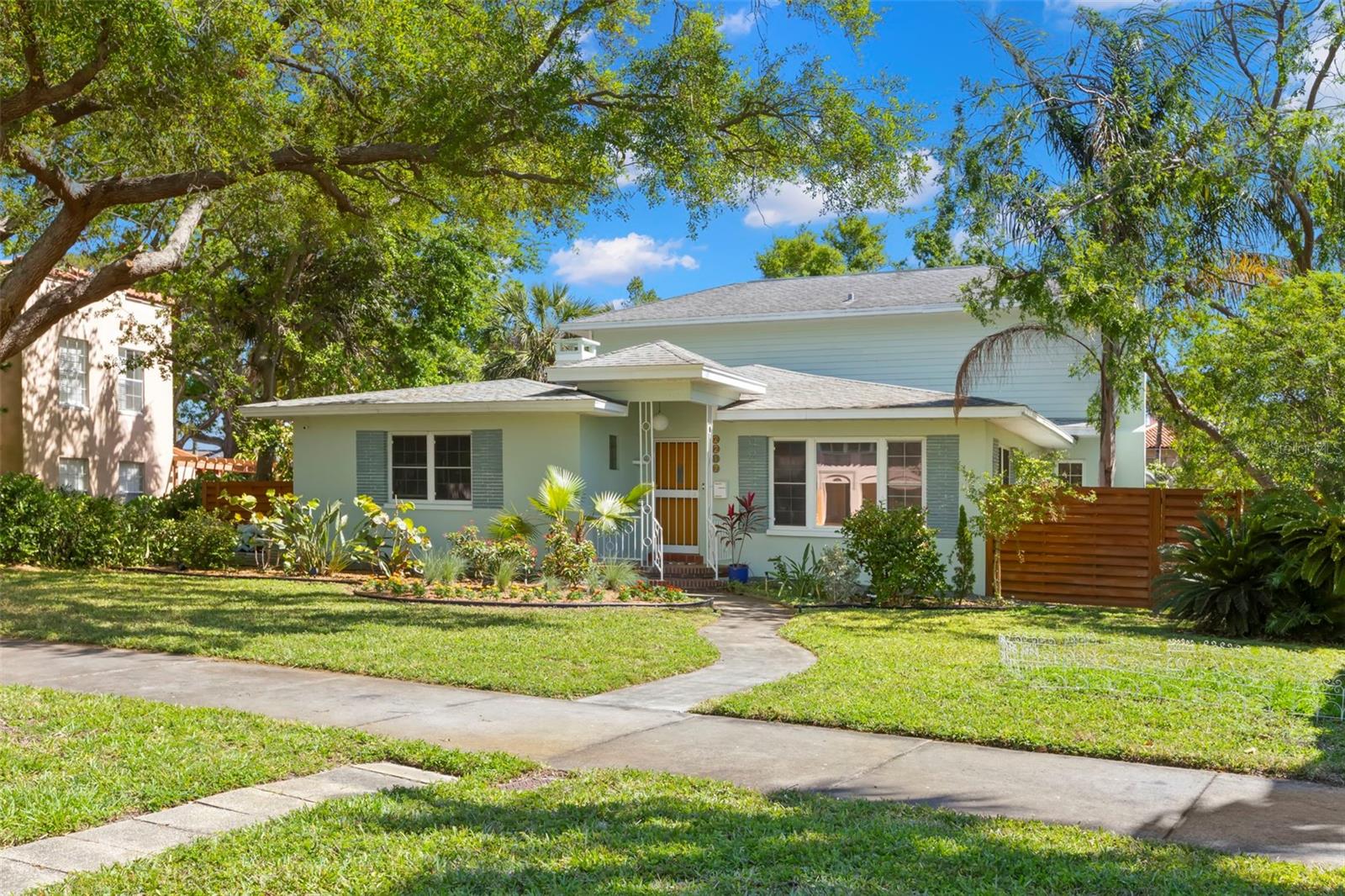 Feel the waterfront breezes one block from Coffee Pot Bayou in the coveted Granada Terrace section of the highly sought after Old Northeast neighborhood! This classic 1950s Mid-Century modern home has never flooded and sits on just over a quarter-acre, offering plenty of room to expand, a rarity in the neighborhood. Inside boasts a blend of vintage and retro period upscale finishes carefully selected by its current owner while blending the modern conveniences of today. The backyard is a gardener's dream with an expansive garden accented by lighted brick pathways and plenty of room for a pool addition. Greet your guests in the inviting living room with original cove ceilings, period archways and oak hardwood floors that have been restored with a matte grey finish for a modern touch. Entertain in the dedicated dining room or in the "retro" kitchen with seating for three at the island and two by the cozy fireplace. The kitchen highlights include European-style, modern solid-wood custom cabinets equipped with roll out, spice and utensil drawers, pantry storage, Big Chill vintage appliances, vintage hardware and lighting, subway tile, quartz countertops and large terrazzo tiles, so unique to mid-century Florida homes. Bringing in groceries is a breeze from the attached two car garage with great storage space. Downstairs are the original two bedrooms with cedar closets and charming period bathrooms. Upstairs, you will find a spacious primary suite with terrace views overlooking the backyard and a pocket view of Coffee Pot Bayou. In addition to the large bedroom, there are two walk-in closets/home office space and the bathroom features dual vanity sinks, a walk-in rain shower and a soaking tub. Experience indoor/outdoor living off the kitchen in the enclosed screened-in lanai with access to the backyard and hot tub/spa. Plenty of room for parking off the alley in the two car garage or on the drivespace for multiple cars. Schedule a private showing today to see a shining example of blending yesterday with today! Don't delay in living the "Florida Lifestyle" with an easy stroll to the waterfront for manatee and dolphin watching or hop on the sidewalk to bike downtown to take in vibrant St. Pete!