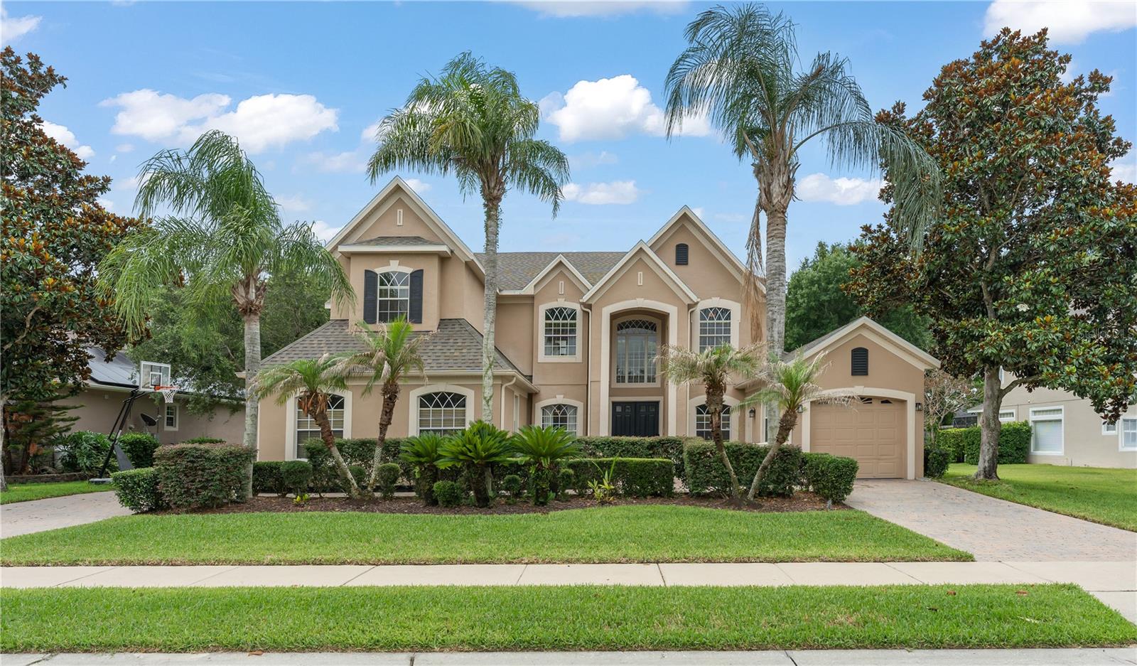 Nestled within the prestigious gated enclave of Bay Isle, this distinguished Toll Brothers home offers a rare combination of sophisticated design, thoughtful craftsmanship, and resort-caliber amenities — all within walking distance of Winter Garden Village and AdventHealth. A soaring two-story foyer and grand living room welcome you with an abundance of natural light streaming through an exceptional array of windows — a hallmark of the home's open, airy character. At the heart of the home lies a commanding gourmet kitchen, completely updated in 2021 with quartz countertops, a handsome marble backsplash, and a professional-grade induction cooktop with custom hood vent. Rich cherry cabinetry, a wall oven, built-in microwave, generous center island, and extensive counter space are all finished with elegant crown molding — flowing seamlessly into the expansive family room with French doors opening to the outdoor living area. The main-level primary suite is a true sanctuary, featuring rich laminate flooring, serene pool and spa views, and architectural transom windows that elevate the abundant natural light. Two oversized walk-in closets with custom built-in organization systems flank a luxurious en-suite bath complete with a dual-sink vanity, deep soaking tub, and a spa-inspired walk-in shower. Upstairs, three additional bedrooms offer both privacy and connection. A private en-suite bedroom with generous walk-in closet is discreetly separated via a catwalk, while two additional bedrooms share a well-appointed Jack-and-Jill bath with individual vanity areas and a shared water closet and tub/shower. Your private home theater is fully equipped for the ultimate cinematic experience — theater seating, a 4K HD projector, Dolby surround sound, all convey with the home. The space also offers flexibility as a fifth bedroom. A loft game area and additional half bath complete the upper level's entertainment suite. Step outside to your private oasis: a sparkling pool and spa enclosed within an oversized screened lanai, complete with an outdoor shower and multiple seating areas ideal for effortless outdoor entertaining. An additional state of the art Clearlight 2 person infrared sauna provides relaxation, and rejuvenation. A three-car split garage — two bays connected to the main home, a third independently accessed — provides exceptional versatility for a workshop, boat storage, collector vehicles, or extra storage. A dedicated EV charging station is already in place. Eight-foot interior doors and extensive crown molding throughout reinforce the home's refined aesthetic. New roof (2019) · Pool pump (2018) · Full kitchen renovation (2021) Bay Isle's gated grounds feature a park, playground, walking trail, and a fishing pier on Black Lake — offering a tranquil, connected lifestyle just minutes from major roadways and every amenity Winter Garden has to offer.