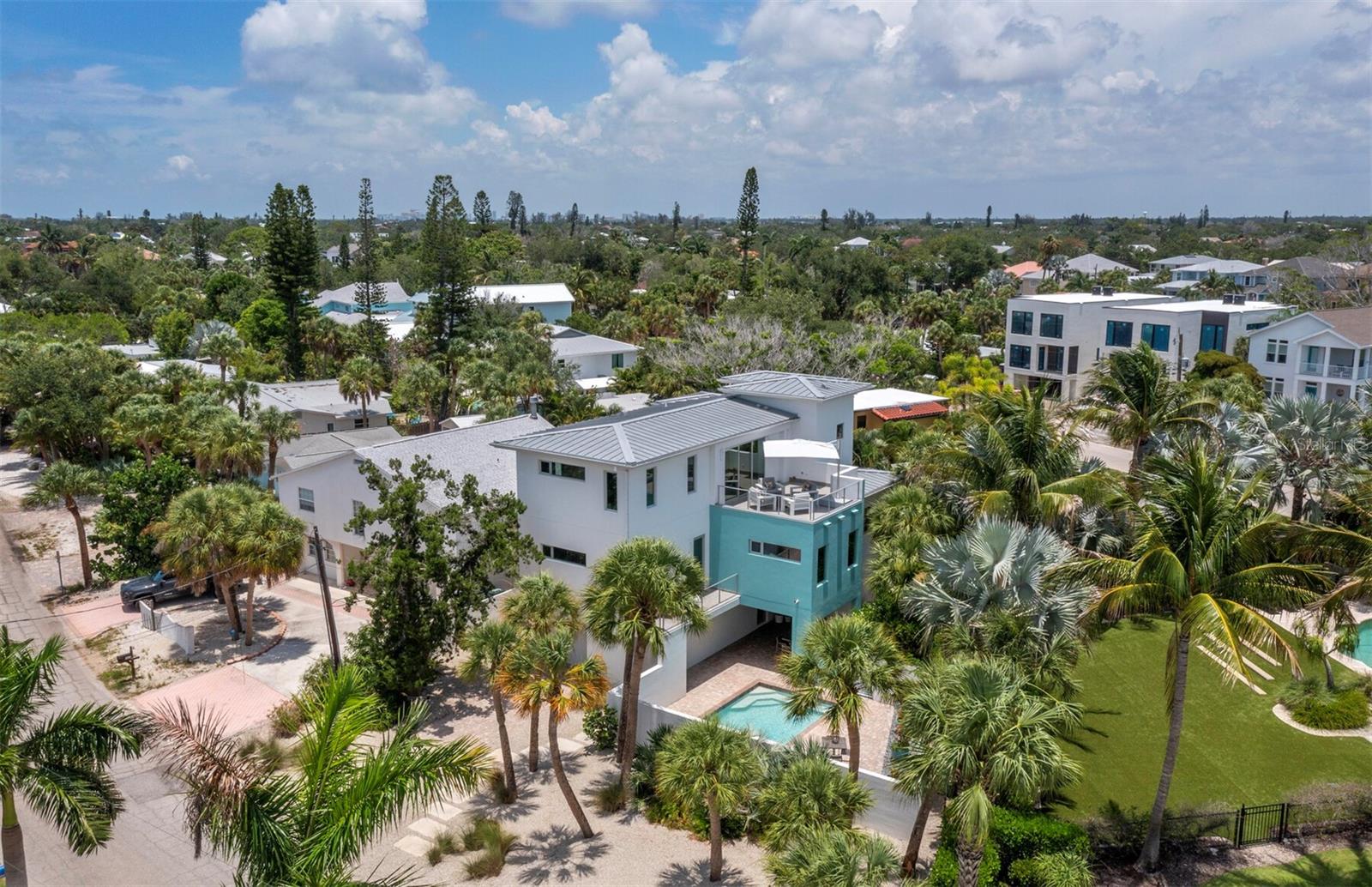 Offered for the first time, 471 Island Circle is a private contemporary coastal retreat designed for modern luxury, effortless living, and the ease of a low-maintenance Siesta Key lifestyle. Ideally positioned in the community of Palm Island, close to Siesta Beach and the charm of Siesta Village, this three-level residence offers a rare blend of privacy, quality construction, and everyday comfort in one of the island’s most desirable settings. From the gated entry and walled-courtyard approach to the private pool area, the home feels wonderfully tucked away while remaining moments from the beach, boutiques, dining, and the relaxed energy that makes Siesta Key so loved.
Built by MGB — My Green Building — with a focus on strength, efficiency, and peace of mind, the residence features solid concrete block construction, reinforced with rebar and poured concrete tied to the roof structure, impact-rated materials, and a low-maintenance exterior. It is an ideal lock-and-leave island home for those who want to enjoy the beauty of coastal living without the demands of a more traditional high-maintenance property.
Inside, a striking floating steel staircase with stainless steel cable detailing creates a memorable first impression, while the elevator provides easy access to all levels. The upper main living level is filled with natural light, with open dining and family spaces designed for comfortable everyday living and easy entertaining. The sleek Cucina Ricci kitchen features abundant contemporary cabinetry, quartz countertops, and premium Thermador appliances, including dual ovens, an icemaker, a five-burner induction cooktop, a concealed refrigerator, and wine refrigeration. A cleverly designed hidden television rotates to be viewed from both the kitchen and living areas. Just beyond, a large west-facing balcony extends the living space outdoors and offers a beautiful setting for open-air dining, sunset cocktails, and evening breezes. A stylish half bath completes the main living level.
The second floor offers three en suite bedrooms; each thoughtfully designed with privacy and comfort in mind. Contemporary baths feature striking tile selections, floating vanities, and clean modern finishes. An additional balcony overlooks the private courtyard pool below, creating a quiet connection between the interiors and outdoor living spaces. A convenient laundry room is located nearby.
Outdoors, the walled pool courtyard is designed for privacy, sunning, swimming, and relaxed coastal enjoyment, offering the feel of a private resort with minimal upkeep. Additional features include two-zone air conditioning for enhanced efficiency, generous storage, and a two-car tandem garage. From morning walks to the beach to evenings near the Village or sunset views from your own balcony, every day here feels like a vacation. When you are ready to explore beyond the island, vibrant downtown Sarasota is just a short drive away, offering world-class dining, arts and culture, and entertainment.
