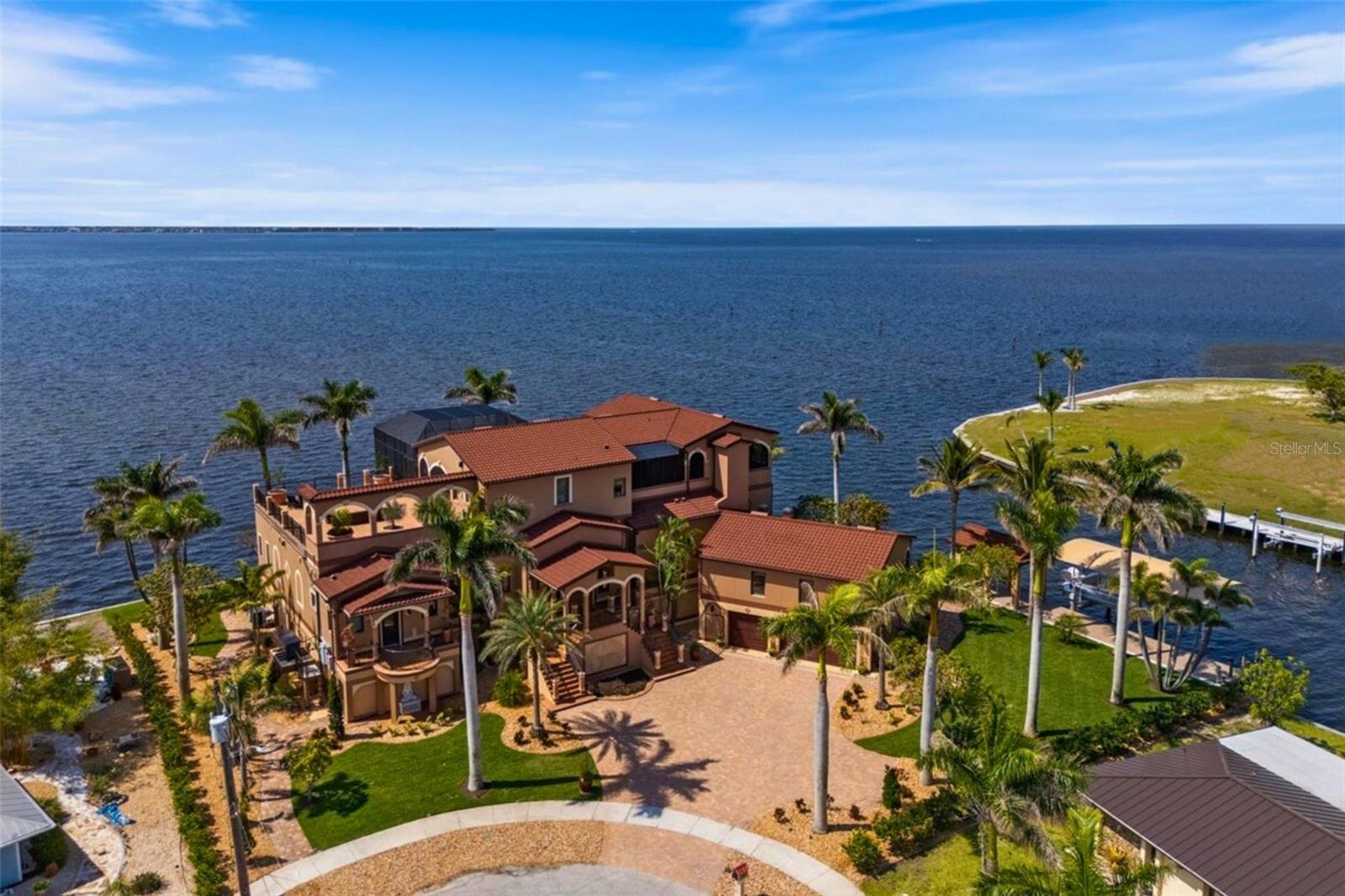 Set on a rare tip lot with approximately 320 feet of pristine waterfront, this one-of-a-kind custom estate delivers an extraordinary blend of architectural elegance, thoughtful engineering, and effortless coastal living. Designed and built as a private retreat, the home spans over 5,500+ sq. ft. of air-conditioned space and more than 7,000+ sq. ft. of seamlessly integrated outdoor living areas, all oriented to showcase uninterrupted views of Charlotte Harbor. Constructed atop 93 deep-set concrete pilings and elevated 15 feet above the waterline, the residence features concrete floors, impact-rated windows, hurricane shutters, and a standby generator with remote monitoring for peace of mind and durability. Inside, custom stonework, intricate imported carvings, and refined finishes lend timeless character to every space. The home offers six spacious bedrooms, each with en-suite baths and private balcony or veranda access, comfortably accommodating up to fifteen guests. The primary suite includes dual walk-in closets, dual commode rooms, a spa tub, oversized shower, and a private lanai with gas fireplace and serene harbor views. A chef’s kitchen anchors the home, featuring commercial-grade appliances, three dishwashers, a wine cooler, and a large island ideal for entertaining. A walk-in butler’s pantry with extensive storage and a coffee or tea bar adds both function and style. Additional interior highlights include art niches, three gas fireplaces, custom cabinetry, and luxury finishes throughout. Outdoor living is elevated by a dramatic two-story screened lanai that doubles the home’s footprint. The main-level infinity-edge pool and spa appear to cascade into the harbor, while the adjacent outdoor kitchen includes a commercial grill, granite countertops, marine-grade cabinetry, a bar with dual-tap kegerator, and a refrigerator—perfect for gatherings of any size. Multiple seating areas, both screened and open-air, provide ideal vantage points for sunrise, sunset, and every moment in between. Boaters will appreciate the new 65-foot dock equipped with shore power, water, lighting, cameras, and a 16,000 lb lift. With direct access to open water and no bridges, it’s a short cruise to Cayo Costa’s beaches or nearby waterfront destinations such as Sarasota, Fort Myers Beach, and Key West. Smart-home features include app-controlled HVAC, indoor and landscape lighting, ceiling fans, garage doors, video surveillance, and pool systems. The irrigation system, fed by a private well, operates remotely with a dedicated sprinkler for every outdoor plant. Connectivity is supported by a Luxul Wi-Fi network with 13 access points, HyperFiber high-speed internet, and Xfinity backup. Additional features include an elevator serving all three levels, dual laundry rooms, a three-car garage with EV charging, professionally landscaped grounds with tropical plantings, fruit-bearing trees, and extensive paver work. Distinct spaces such as a media suite, octagonal view room, study, and formal dining room complete the interior. Located in a peaceful community just 15 minutes from Punta Gorda Airport and within easy reach of Tampa, Naples, and Sarasota, this waterfront residence combines comfort, sophistication, and extraordinary views!!