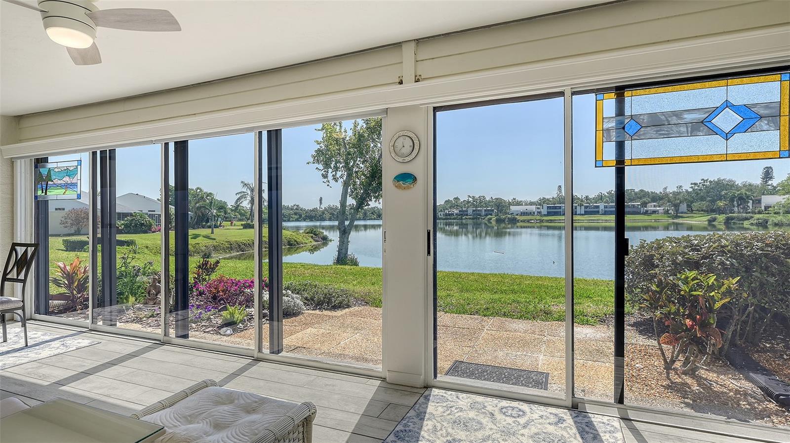 Once you walk up to the front door & peer through the open concept living area, your eyes will be focused on the large reflective pond, just beyond your rear sliders. This is one of the most tranquil views throughout the day, from glistening of the sunrise over the water every morning to the abundance of the variety of birds & ducks that frequent the pond to the amazing sparkle of another sunset.  The interior is quite as stunning as well. You will first come upon the creative design of fabulous wood cabinets, all with soft close, along with an amazing wall of floor to ceiling pantry/small appliance storage, classy granite counters, pull outs for your pots & pans with plenty of storage & counter space. Great for all your extras, entertaining pieces & food prep for your holiday gatherings.  Your open concept living makes it easy to converse with your guests from this area of the home. A bistro table would fit nicely under the front kitchen window, in front of the plantation shutters. Barstool seating at the open counter for casual meals or for more formal seating, the dining table would accommodate that special gathering. From here it flows seamlessly into your large living room. This area of the home has beautiful neutral tiled floors that blend beautifully with the neutral palate, perfect for a Florida home. From here let's continue onto the spacious lanai with a wall of sliders to enjoy the ambiance of this remarkable backyard, starting with the vibrant colors in the flower garden to the tranquility of watching the ripples in the pond.  No doubt this will be your go to area of the home! Also on your lanai, a generous size storage closed which occupies your full-size washer & dryer. Enjoy custom pull-down light filtering privacy window treatments the full length of your sliders. Stepping back inside, you can enter the 2nd set of sliders from the lanai, taking you right into your spacious primary suite. You come upon a generous size walk in closet along with a wall of closets for more than adequate room for your wardrobe. This area has engineered hardwood floors to enhance the tranquility of this space. The ensuite has granite counters & plenty of counter space & storage for all your essentials.  The shower area with separate commode area is perfect for privacy, allowing access to each area. Now as we head back to the front of the home, we come upon the guest room, complete with ensuite.  This room was thoughtfully designed for space & storage with a beautiful full size Murphy Bed.  This community consists of 88 acres, making it nothing short of paradise for those who enjoy nature, the sights of colorful foliage & the sounds of nature. There are trails throughout for a relaxing walk. Community is within close proximity to everyday essentials, including 3 airports between 15 minutes to less than an hour away, access to major roads & interstates, plus the beaches of Anna Maria Island, just 15 minutes to the beautiful Gulf waters & IMG. Activities nearby include multiple golf courses, parks & recreation, theater, boating & fishing, Spring Training, cruise ports & comedy shows just to name a few. This area has access to a magnitude of fun things to see & do! Community also offers 2 heated pools & hot tubs, tennis plus pickle ball.
This home is perfect for year-round living or your snowbird residence. Leave with peace of mind from your newly installed electronic hurricaine shutters, simply just flip a switch! Furnishings negotiable.