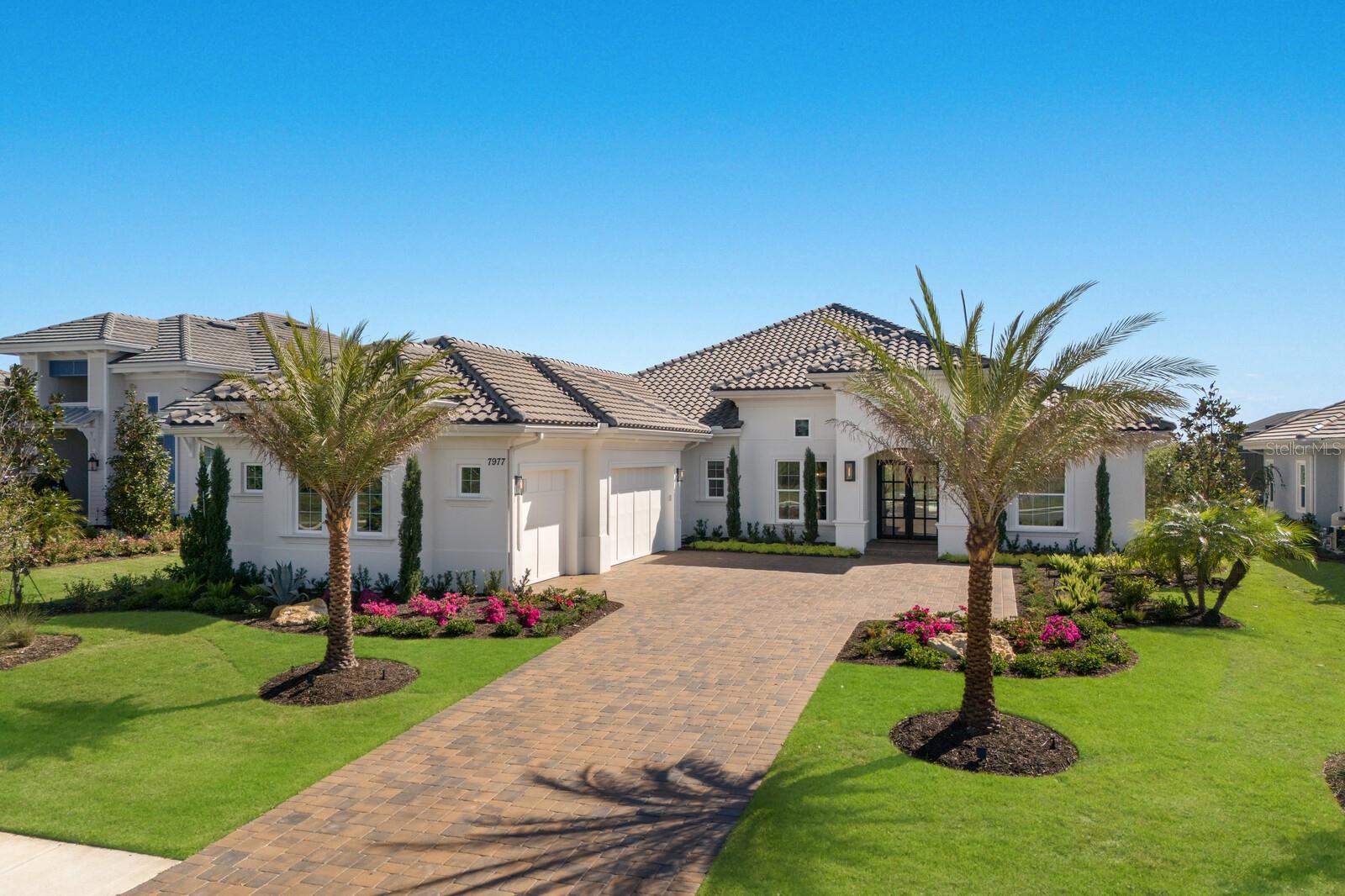 Curated by an interior designer, this professionally refined residence was built in 2024 on a stunning lot inside the exclusive gated community of The Lake Club boasting surrounding views from the front and back of the home to enjoy both sunrises and sunsets. Encompassing 3,754 square feet of open one-story living,  this customized Stock Home built in 2024 exudes stylishly planned indoor and outdoor spaces, accentuated volume ceilings, skillfully selected finishes, Restoration Hardware light fixtures, and, of course, IMPACT windows/doors/sliders.

An expansive outdoor retreat elevates the Florida living experience with a panoramic screened lanai, extensive open and under cover spaces grounded with travertine pavers, soaring ceilings, full summer kitchen, PebbleTec heated saltwater pool/spa with sun shelf, gas fireplace and even a fenced dog run.  Ten foot impact glass sliders seamlessly connect the outdoor oasis to a luxuriantly welcoming great room, dining area and gourmet kitchen with sumptuous wood floors crowned with stunning ceiling treatments, accent wall, and designer light fixtures creating a sophisticated and open continuity of space.  Meanwhile the kitchen further accentuates with dual layers of wood cabinetry, elevated quartz counters, high-performance Jenn-Air appliances, induction cook top yet also pre-plumbed for gas, and a wet bar with wine fridge off the formal dining room.  An impressive club room directly off lanai beckons for entertaining with soaring ceilings and windows with glorious views beyond. 

Relax and unwind in the owner’s quarters positioned on a private wing, offering double tray ceilings, large scale windows, direct lanai access, wood flooring, two oversized walk-in customized closets, privacy remote screens, and a luxuriously appointed bath with dual station vanity, an oversized shower with designer tile, a large soaking tub, and separate water closet.  On a separate wing of the home there are three additional guest suites generous in size, all with walk-in closets, two offer ensuite full baths, while the third guest room is just off the home’s fourth full bath. The residence also offers an impressive office behind double-entry doors just off the entry foyer. Other notable highlights of this newly built all-encompassing 5,963 total square foot residence includes a brilliantly finished laundry room, beautiful built-in mud room area, a fenced in dog run, double-insulated walls in the primary suite/laundry room and office, tankless water heater, all impact windows and doors, water filtration system, reverse osmosis in the kitchen, Smarthome automation, and an oversized three car garage with electric car charging station.

This bespoke offering defines modern refinement beckoning a lifestyle fulfilled and the pinnacle of luxury living in The Lake Club, where residents enjoy access to a wealth of amenities, including two resort-style heated pools, Grande Clubhouse with fine dining and bar area, a fitness center, spa, tennis courts, pickleball, a playground, dog park, and services of a full-time concierge and activities director.
