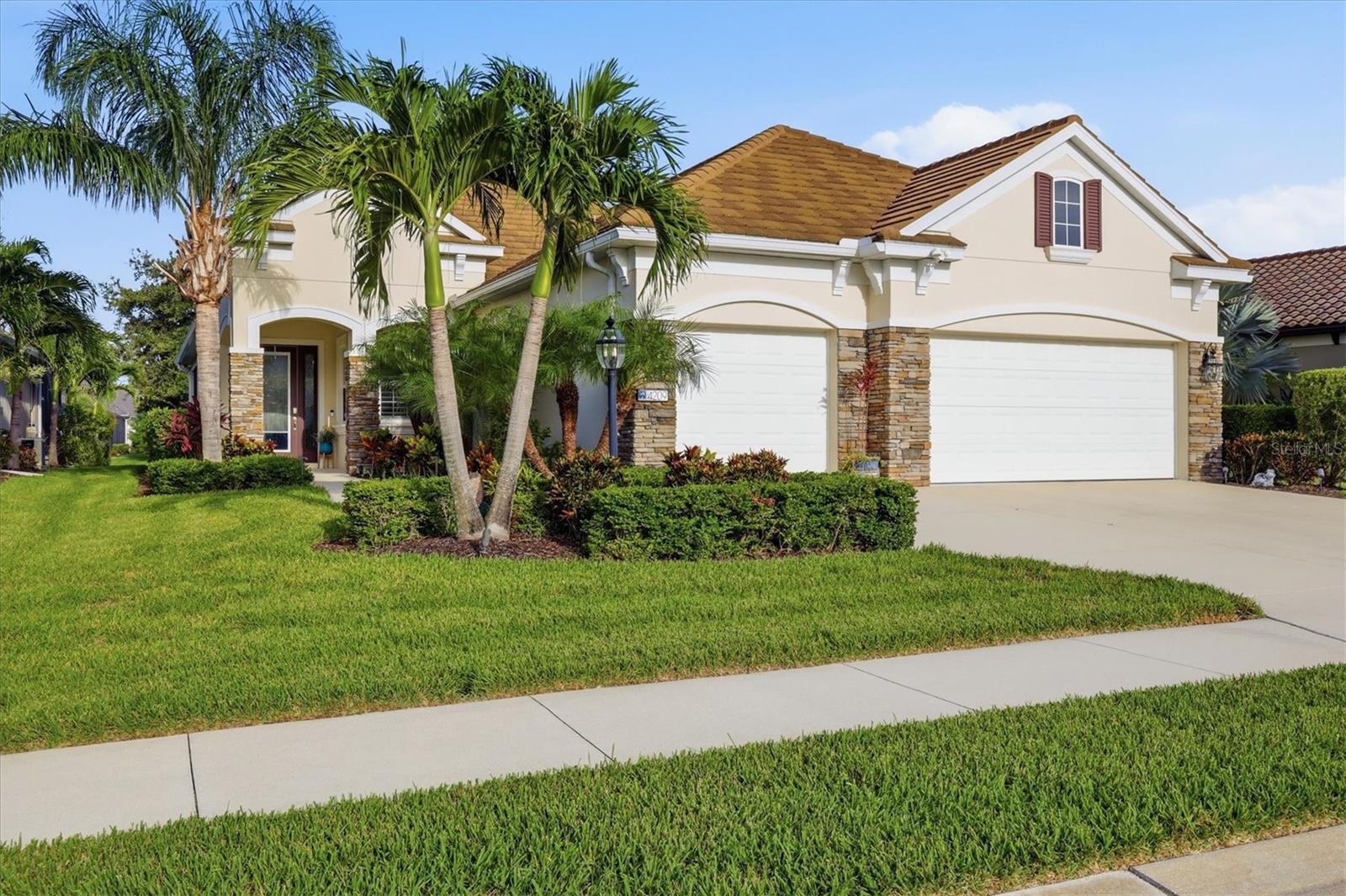 Nestled within the sought-after gated community of Indigo in Lakewood Ranch, this beautifully appointed Neal Communities residence showcases refined finishes, thoughtful upgrades, and an effortless lifestyle that embodies the very best of Lakewood Ranch living. Inspired by timeless coastal design, this exceptional home features an open split-bedroom floor plan with three bedrooms, a private office, two-and-a-half baths, soaring 10-foot tray ceilings, crown molding, abundant natural light, and tranquil lake views. Surrounded by lush tropical landscaping and enhanced by exceptional curb appeal, every detail has been thoughtfully designed to create a home that is as welcoming outside as it is inside.

At the heart of the home, the light-filled great room flows effortlessly into the dining area and chef-inspired kitchen, creating an inviting space that's equally suited for entertaining guests or enjoying quiet evenings at home. Expansive sliding glass doors frame peaceful lake views while opening to the oversized screened lanai, seamlessly blending indoor and outdoor living.

Designed with both beauty and function in mind, the kitchen is anchored by a generous island overlooking the living area and features quartz countertops, a new five-burner natural gas cooktop, designer backsplash, abundant cabinetry, and a spacious walk-in pantry. Whether preparing everyday meals or hosting family and friends, this space was designed to be the heart of the home.

The privately situated owner's retreat offers peaceful lake views, two walk-in closets, and a luxurious ensuite with dual vanities and a large walk-in shower filled with natural light. Two additional guest bedrooms and a dedicated office are thoughtfully positioned on the opposite side of the home, providing privacy and flexibility for family, guests, or working remotely.

Refined upgrades continue throughout, including sleek modern plantation shutters, automated interior blinds on the sliding glass doors, designer lighting, and carefully selected finishes that create a clean, elevated aesthetic. Even the three-car garage has been exceptionally designed with custom built-in cabinetry and three heavy-duty overhead storage rack: one above each bay providing outstanding organization and storage.

Indigo is a vibrant, active community with a full-time on-site manager and a dedicated activities director who curates an extensive calendar of events for all ages. Residents also enjoy a resort-style heated pool and spa at the main clubhouse, five cabanas with ample seating, four pickleball courts, two bocce ball courts, a 24-hour fitness center, a meeting/banquet room, and a playground.

Ideally situated in the heart of Lakewood Ranch, you'll enjoy convenient access to premier shopping, exceptional dining, championship golf, top-rated schools, everyday conveniences, and Florida's world-renowned Gulf Coast beaches.

Offering refined finishes, thoughtful upgrades, exceptional outdoor living, and the relaxed elegance that defines Lakewood Ranch, this beautifully designed residence is ready to welcome YOU home.