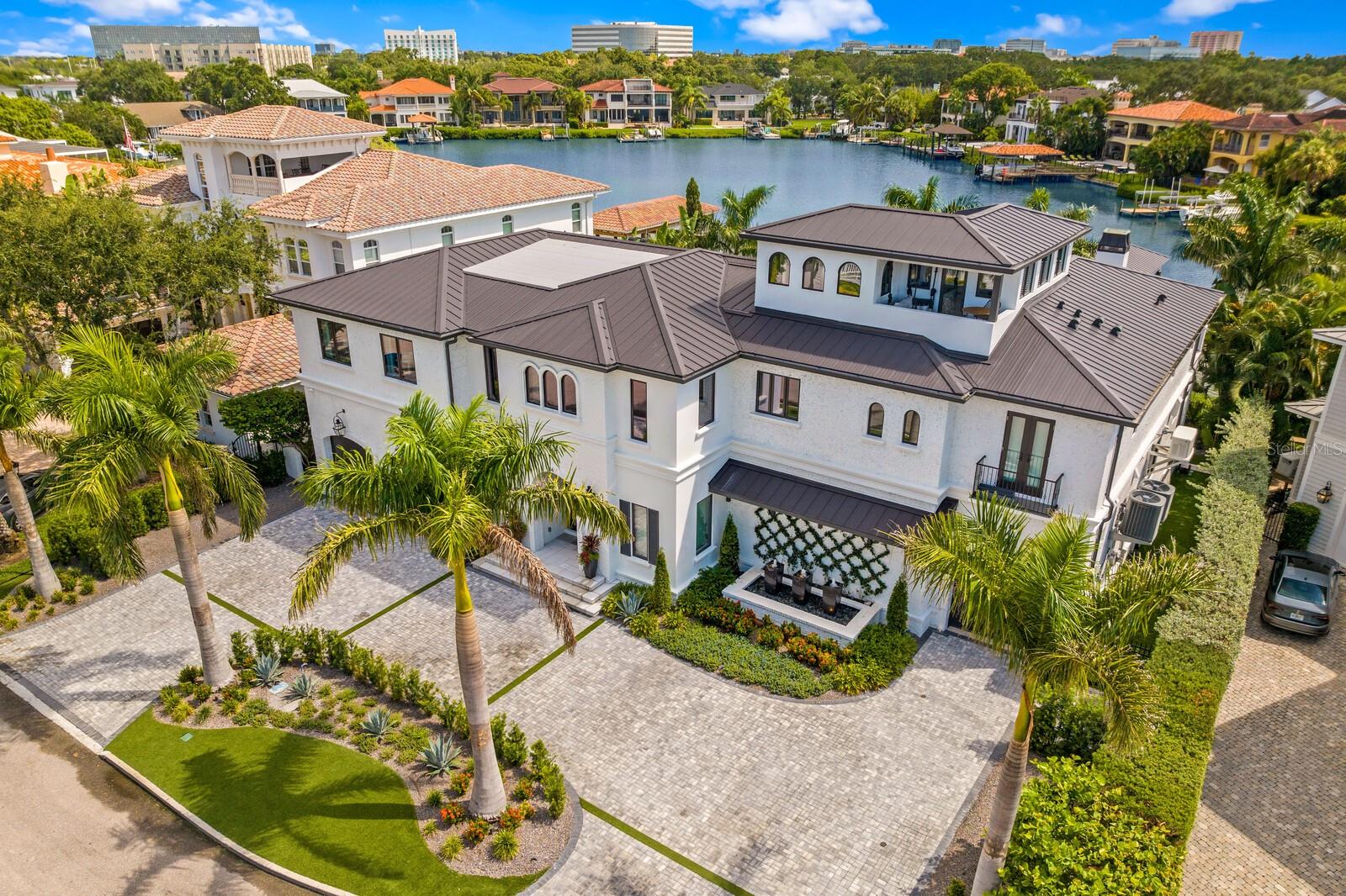 Exquisite Beach Park Waterfront Estate – A Masterpiece of Modern Elegance and Sophisticated Luxury. Meticulously designed, masterfully rebuilt and completely renovated LIKE NEW waterfront mansion offering state-of-the-art construction (2024) and opulent finishes for a coveted South Tampa waterfront lifestyle. Striking European-inspired design, an oversized circular drive, and custom arched glass front door welcome you to this oasis on the protected deep-water “Pirate’s Cove.” Boasting sweeping water views, nearly 7,000 SF of refined living spaces, 6 Bedrooms, 6.5 Baths and 3+ Car Garages. Offering exquisite details and bespoke finishes, this is more than a home; it’s a statement of modern elegance.  A dramatic marble foyer opens to the dining room with Pecky Cypress beams, and superior chef’s kitchen for upscale entertaining. The kitchen features dual marble waterfall islands, Sub-Zero appliances, walk-in pantry, beverage/wine bars, and a seamless pass-through window to the outdoor waterfront entertainment area. The first level flows into an inviting living room anchored by a sleek gas fireplace and retracting EuroWall sliding doors to the backyard oasis, along with a private guest suite, pool bath, and spa-like cabana room gym. The second level features five ensuite bedrooms with marble bathrooms, an oversized laundry room with dual washers/dryers, elevator, an additional loft area with beverage bar, large terrace overlooking the water, and a state-of-the-art theatre. Immerse yourself in a cinematic experience with surround sound, starlight ceiling, and layered seating. Ascend the custom-steel and glass staircase to the private third-level office featuring a covered terrace and amazing 360-degree water views where you can enjoy stunning open-water sunsets. The primary suite is an elegant experience with foyer entry, full retracting glass doors to a waterfront terrace and linear fireplace overlooking the pool, relaxed sitting area, automated window panels, designer closet, and lavish bath with heated marble floor and appointments worthy of the very best five-star resorts.  Refined living continues outdoors to the expansive loggia, with Pecky cypress ceiling, linear fire features, heated knife-edge pool, infinity-edge spa, and a private dock overlooking the coveted deep-water Cove, perfect for access directly to the open water, or observing the dolphin and manatee from your back yard.  Enjoy alfresco dining, entertain large gatherings, or unwind in the seating areas with automated screens, surrounded by meticulous resort-style landscaping. Featuring sunset views of Tampa Bay and sunrises over Pirates Cove, this enclave of fewer than 20 luxury homes provide a decadent waterfront lifestyle. Enjoy direct access to Tampa Bay with a 40’ covered boat lift with 30,000 lb lift and additional slip.  Thoughtful luxury design features throughout include white oak flooring with brass and marble inlays, automated Lutron shades and elegant window panels, designer wallpaper, bronze mirrors, glass panel and spiral stairways, custom closet systems, and water views from every room.  Innovative technology provides efficiency and comfort with Control4 home automation, security cameras, whole home generator, new impact doors/windows/roofing, new plumbing/electric/HVAC systems, and whole home water filtration.  Situated on a cul-de-sac with Charleston-inspired streetlamps and no visible overhead powerlines.