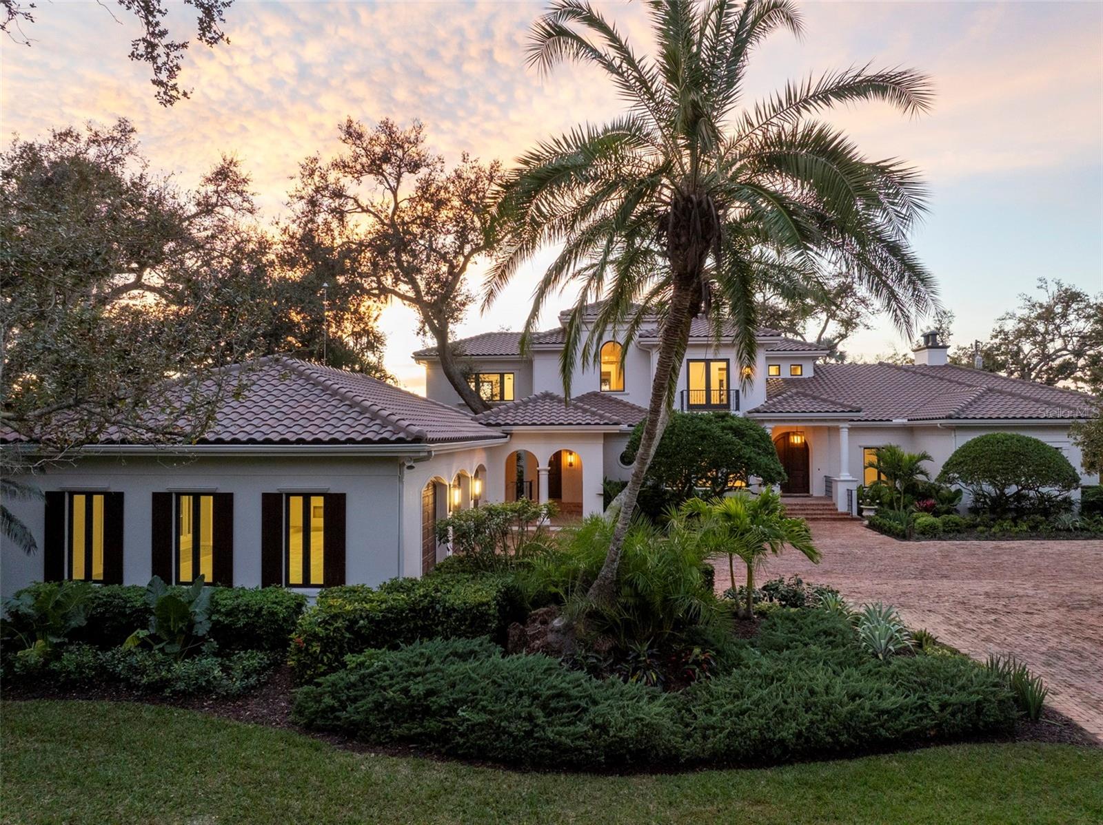 One of Sarasota’s greatest bayfront estates, this stunning 1.38 acre waterfront home has recently undergone a comprehensive renovation throughout, enhancing every room with refined finishes and modern systems while preserving its timeless architectural character. Hidden away at the end of Southwest Drive within the coveted Cherokee Park neighborhood, this 5-bedroom home offers exceptional seclusion and privacy, surrounded by lush, verdant landscaping, specimen trees and mature oaks, with tranquil water views providing a serene backdrop throughout the entire home. A masterpiece by design, this architectural gem was designed by esteemed architect Clifford Scholtz and built with impeccable craftsmanship by Rich Perrone of Perrone Construction. Among the recent exterior improvements are a new roof and gutters, fresh exterior paint, new decorative landscape lighting, and a refreshed outdoor shower. Inside, thoughtfully curated modern finishes and updates seamlessly blend with classic architectural details such as columns, archways, and a mahogany-paneled office, creating interiors that feel bright, open, and timeless. New European white oak flooring flows through the main living areas, while Stark carpeting adds warmth to the staircase, select bedrooms, and the bonus room. A culinary enthusiast’s dream, the completely updated kitchen boasts Taj Mahal leathered stone countertops, White Haze dolomite backsplash, a micro cement hood, painted cabinetry, an oversized island, new sinks and faucets, a Sub-Zero fridge/freezer, and more. The charming breakfast area and adjacent family room, featuring a new micro cement fireplace with Taj Mahal hearth, are set against a backdrop of expansive windows and glass doors that capture picturesque bay views. A luxurious and peaceful retreat, the elaborate primary suite features a beautifully updated bath showcasing new vanities with Taj Mahal countertops and Brizo fixtures, plus new flooring, soaking tub, and walk-in shower. Secondary baths throughout the home have also been refreshed. Covered patios and loggias extend from the main living areas, creating ideal spaces for relaxation and enjoyment. Upstairs, the expansive gathering room impresses with its custom Perla Venata quartzite bar, freshly painted ceiling beams, large windows, and balcony access overlooking the bay, pool, and lush grounds. This is the perfect perch to enjoy large gatherings, relax at the bar, shoot pool, or have friends and family over on game day. Outside, the property unfolds as a private oasis, with a screened porch featuring Chicago brick pavers, a Wolf gas grill, Sub-Zero fridge, and refreshed finishes including a tiled backsplash, updated hardware, new sink and faucet, and refinished cabinetry. Chicago brick pavers also surround the free-form pool, creating a cohesive outdoor living environment. At the water’s edge, boaters will delight in the protected deep-water boat basin with two lifts (10,000-lb. and 16,000-lb. capacities), providing effortless maritime adventures. A detached oversized 3-car garage, connected by a covered walkway, provides ample space for storage or workshop use. Additional updates of note include updated HVAC systems, tankless water heaters, and modernized electrical throughout. A whole house generator rounds out the superlative systems. This exquisitely updated estate represents a rare offering where timeless elegance meets modern sophistication on one of Sarasota's most extraordinary waterfront settings.