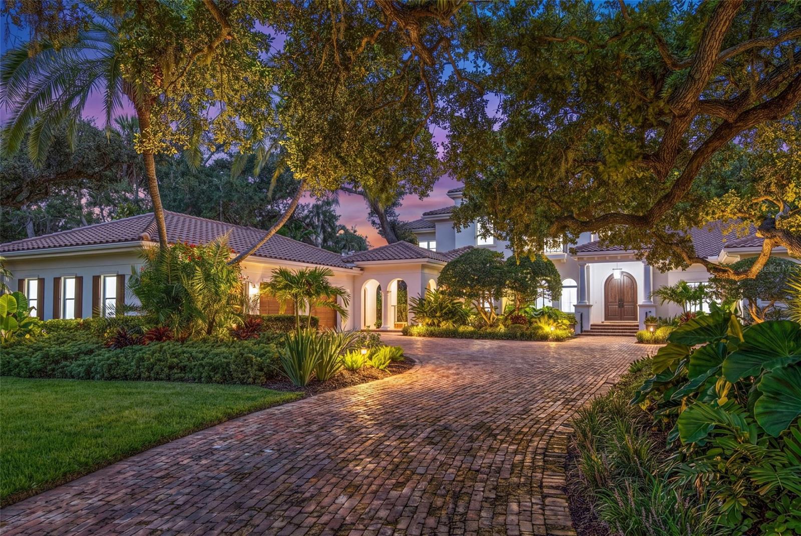 One of Sarasota’s greatest bayfront estates, this stunning 1.38 acre waterfront home has recently undergone a comprehensive renovation throughout, enhancing every room with refined finishes and modern systems while preserving its timeless architectural character. Hidden away at the end of Southwest Drive within the coveted Cherokee Park neighborhood, this 5-bedroom home offers exceptional seclusion and privacy, surrounded by lush, verdant landscaping, specimen trees and mature oaks, with tranquil water views providing a serene backdrop throughout the entire home. A masterpiece by design, this architectural gem was designed by esteemed architect Clifford Scholtz and built with impeccable craftsmanship by Rich Perrone of Perrone Construction. Among the recent exterior improvements are a new roof and gutters, fresh exterior paint, new decorative landscape lighting, and a refreshed outdoor shower. Inside, thoughtfully curated modern finishes and updates seamlessly blend with classic architectural details such as columns, archways, and a mahogany-paneled office, creating interiors that feel bright, open, and timeless. New European white oak flooring flows through the main living areas, while Stark carpeting adds warmth to the staircase, select bedrooms, and the bonus room. A culinary enthusiast’s dream, the completely updated kitchen boasts Taj Mahal leathered stone countertops, White Haze dolomite backsplash, a micro cement hood, painted cabinetry, an oversized island, new sinks and faucets, a Sub-Zero fridge/freezer, and more. The charming breakfast area and adjacent family room, featuring a new micro cement fireplace with Taj Mahal hearth, are set against a backdrop of expansive windows and glass doors that capture picturesque bay views. A luxurious and peaceful retreat, the elaborate primary suite features a beautifully updated bath showcasing new vanities with Taj Mahal countertops and Brizo fixtures, plus new flooring, soaking tub, and walk-in shower. Secondary baths throughout the home have also been refreshed. Covered patios and loggias extend from the main living areas, creating ideal spaces for relaxation and enjoyment. Upstairs, the expansive gathering room impresses with its custom Perla Venata quartzite bar, freshly painted ceiling beams, large windows, and balcony access overlooking the bay, pool, and lush grounds. This is the perfect perch to enjoy large gatherings, relax at the bar, shoot pool, or have friends and family over on game day. Outside, the property unfolds as a private oasis, with a screened porch featuring Chicago brick pavers, a Wolf gas grill, Sub-Zero fridge, and refreshed finishes including a tiled backsplash, updated hardware, new sink and faucet, and refinished cabinetry. Chicago brick pavers also surround the free-form pool, creating a cohesive outdoor living environment. At the water’s edge, boaters will delight in the protected deep-water boat basin with two lifts (10,000-lb. and 16,000-lb. capacities), providing effortless maritime adventures. A detached oversized 3-car garage, connected by a covered walkway, provides ample space for storage or workshop use. Additional updates of note include updated HVAC systems, tankless water heaters, and modernized electrical throughout. A whole house generator rounds out the superlative systems. This exquisitely updated estate represents a rare offering where timeless elegance meets modern sophistication on one of Sarasota's most extraordinary waterfront settings.