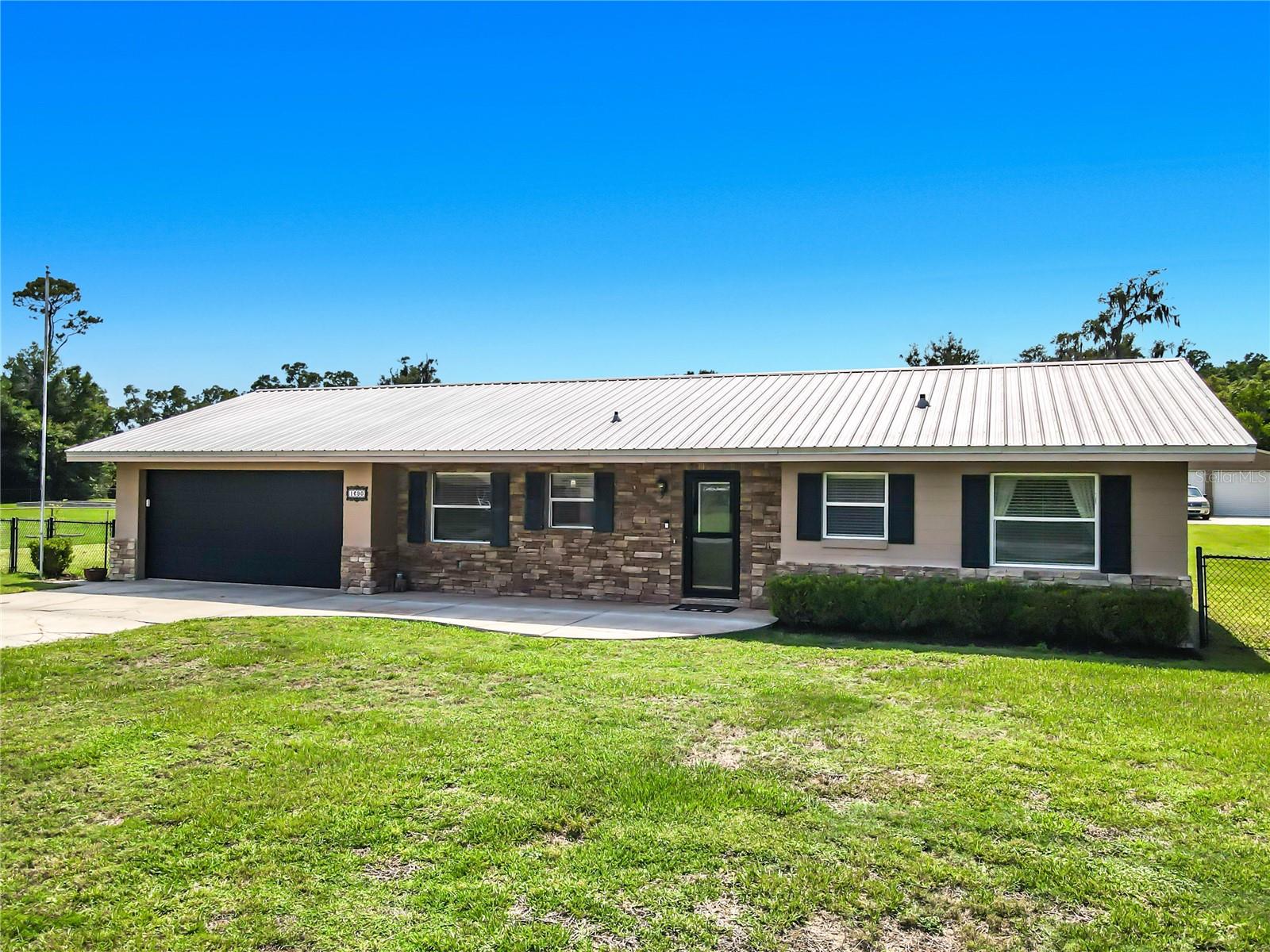 Welcome to this well-maintained 3-bedroom, 2-bath concrete block and brick home with a 2017 METAL ROOF situated on a beautifully FENCED 1.06-ACRE lot in a highly desirable DeLand location. Offering the perfect combination of space and convenience, this property provides room to spread out while remaining close to shopping, dining, healthcare, and everyday necessities.

Inside, you'll appreciate the desirable split-bedroom floor plan, providing privacy between the primary suite and guest bedrooms. The kitchen features 42-inch cabinets and stainless steel appliances.  A solar dome skylight fills the living area with natural light, creating a bright and inviting atmosphere throughout the day.

The primary suite is designed for comfort and style, featuring rustic barn doors that lead to the private modern bath with a step-in shower and a generous walk-in closet.

Enjoy Florida living year-round from the screened Florida room overlooking the backyard and acreage. Outside, the fully fenced property offers exceptional versatility with a double gate providing easy access to the impressive 24' x 30' METAL WORKSHOP/storage building complete with a concrete pad in front. Whether you need space for hobbies, equipment, vehicles, boats, or recreational toys, this property has you covered.  

Located just minutes from shopping, restaurants, medical facilities, and downtown DeLand, this property also offers easy access to Florida's attractions. Enjoy a short drive to the beach or reach Orlando International Airport, Disney World, and other Orlando destinations in about an hour.

If you've been searching for a solid block home with acreage, a large workshop, and an outstanding location, this property is a must-see.