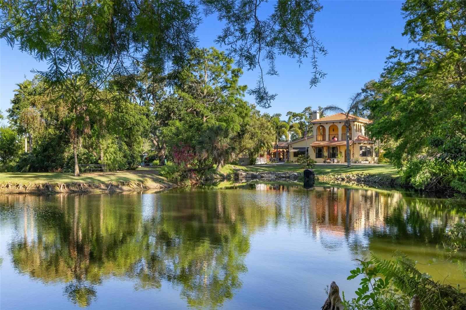 AN EXQUISITE 3 ACRE ESTATE IN THE HEART OF SARASOTA WITH MAIN RESIDENCE AND GUEST HOUSE. Behind a rustic hand crafted door door lies a world of timeless elegance and inspired living. Nestled on approximately 3 acres next to a protected preserve, this captivating estate blends Old World charm with Florida's natural beauty to create a truly one-of-a-kind retreat. Every corner tells a story—crafted with unique architectural elements, curated antiques, and artistic touches that evoke the feeling of a European villa.

From the moment you enter, you're greeted with warm, inviting spaces designed for both quiet reflection and joyful entertaining. Inside, a chef's kitchen, a pizza oven, and multiple dining areas are designed for memorable gatherings, while themed rooms and intimate spaces provide moments of delight and discovery. The primary suite is situated on the upper level and offers a luxurious escape, complete with spa-like features and private outdoor access.

Outdoors, explore tranquil gardens, a peaceful lake, mature trees, and thoughtfully designed areas for dining, gathering, and relaxation. A covered portico connects to an impressive pool and entertaining area, anchored by an outdoor fireplace and a fully equipped kitchen—perfect for alfresco dining and sunset soirees. Whether hosting a grand celebration or enjoying a quiet evening under the stars, the outdoor spaces are designed for unforgettable moments.

A detached workshop, multiple garages, and whimsical retreat spaces add to the estate's versatility and charm. The MLS square footage does not include the guest house (1,377 sq ft additional) or the charming cottage—each offering flexible options for guests, extended family or creative space.