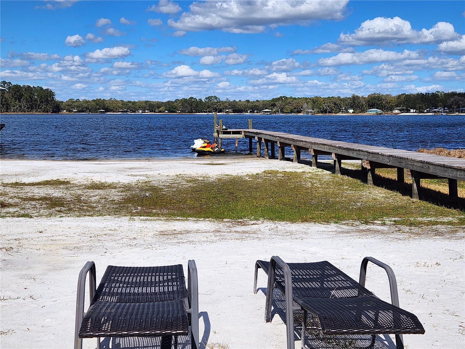 Island Lake Retreat! Come enjoy all that lake life has to offer from your own sandy beach area and private dock on beautiful spring fed Island Lake. This updated 3/2 split plan home features a light and bright kitchen with stainless steel appliances overlooking a very spacious living room. In addition to the 3 bedrooms, there is a versatile bonus room with a walk-in closet and French doors leading to a 16x27 screened porch that overlooks the lake. The primary suite offers a walk-in closet, a double sink vanity and an oversized step-in tiled shower. Additional features include attractive vinyl plank flooring throughout, an inside laundry room, a tiled guest shower, a metal roof and a storage shed. Conveniently located between Ocala, Gainesville and Palatka.