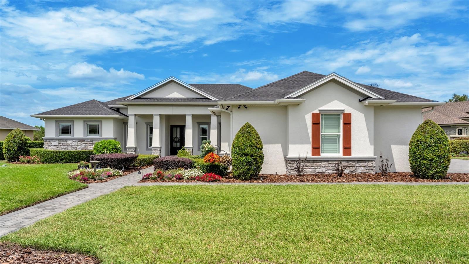 This stunning custom home, masterfully built in 2020 by Duane McQuillen, is tucked within the prestigious gated community of Hallam Preserve and showcases an exceptional blend of craftsmanship, elegance, and modern comfort. Designed with intention and finished with luxury in mind, the home offers 4 bedrooms, 3 full bathrooms, a dedicated office, and an impressive 3-car garage. The moment you step inside, you’re welcomed by rich wood-look tile flooring, soaring ceilings, refined crown molding, and an expansive open layout that creates a seamless flow throughout the living spaces. The gourmet kitchen is a showpiece, featuring marble countertops, premium white cafe deluxe appliances with gold handles, including an induction cooktop, custom amish built cabinetry, a designer marble backsplash, a built-in bar with a wine refrigerator, and an oversized walk-in pantry. It opens effortlessly to the spacious living room, where a custom built-in entertainment center, elegant shelving, and a tray ceiling with integrated lighting elevate the atmosphere. The primary suite is a luxurious retreat offering tray ceilings, private access to the patio, dual walk-in closets with custom built-ins, and a spa-inspired en-suite bathroom with dual vanities and a beautifully tiled walk-in shower. The second bedroom includes its own walk-in closet and private full bathroom, ideal for guests seeking comfort and privacy. Bedrooms three and four are thoughtfully positioned in a tri-split layout off the patio, separated by the third full bathroom, making the home ideal for families, guests, or multigenerational living. The expansive screened-in pavered patio is designed for elevated outdoor living, complete with a full outdoor kitchen, generous seating areas, upgraded landscaping, and an iron fenced-in yard that enhances both beauty and functionality. The 3-car garage has been meticulously upgraded with custom built-in shelving, premium coated flooring, enhanced lighting, an EV charger, a dedicated mini-split system, and a large floored attic accessible by a built-in stairway. Additional features include a tankless water heater, whole-home generator system, water softener, and a comprehensive security system. Residents of Hallam Preserve enjoy access to a community pool and playground, and the home is ideally located near major retailers, the Polk Parkway, and the new Orlando Health Hospital—offering a lifestyle of luxury, convenience, and exceptional quality.