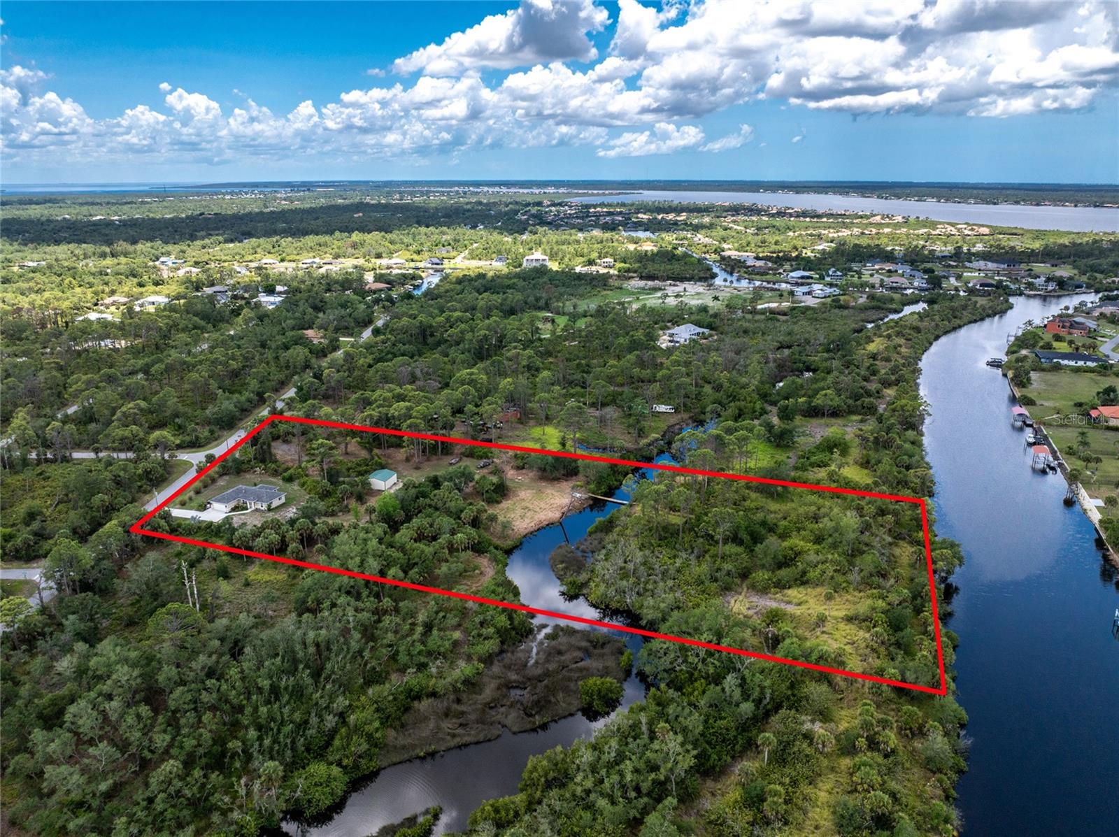 Built in 2020 and sitting on an incredible 5-acre Gulf access property in Port Charlotte, this one-of-a-kind estate offers a combination of features that are extremely hard to find in Southwest Florida. Outdoor enthusiasts will appreciate the privacy, room to spread out, no deed restrictions, detached metal building, and even a private 200-yard shooting range with a 40-foot dirt berm backstop. The property fronts a Over 340 feet of Saltwater canal frontage with the potential to add a dock and enjoy boating access to the Gulf. There is plenty of room for RVs, boats, trailers, and all the toys, plus space for a large future pool with the home positioned for desirable southern rear exposure. The detached metal building sits on a concrete slab and includes power, water, and gas, making it ideal for a workshop, storage, garage space, or hobbies. The owner has has incorporated gas features throughout including a 500-gallon buried LP tank, 22KW whole-house generator, tankless instant hot water heater, gas line rough-in for a gas clothes dryer if desired, gas log fireplace in the living room, gas wall fireplaces in the primary bedroom and den/guest bedroom, and decorative gas lantern-style exterior lighting at the front entrance and garage that creates a unique look rarely seen in residential properties. The home itself is loaded with upgrades including spray foam insulation in the house and garage, insulated garage door, insulated hot water lines, whole-house wired audio, wood-look porcelain tile flooring throughout, wood cabinetry, granite countertops, stainless steel appliances, and matching quality finishes in the bathrooms. The large screened lanai features an oversized picture window screen panel for unobstructed views of the property. Despite the private setting, you are still conveniently located near shopping, restaurants, Port Charlotte amenities, and the beaches of Englewood and Boca Grande.  Scroll through to the end to see all the great photography on this one and then call to set up your private showing!