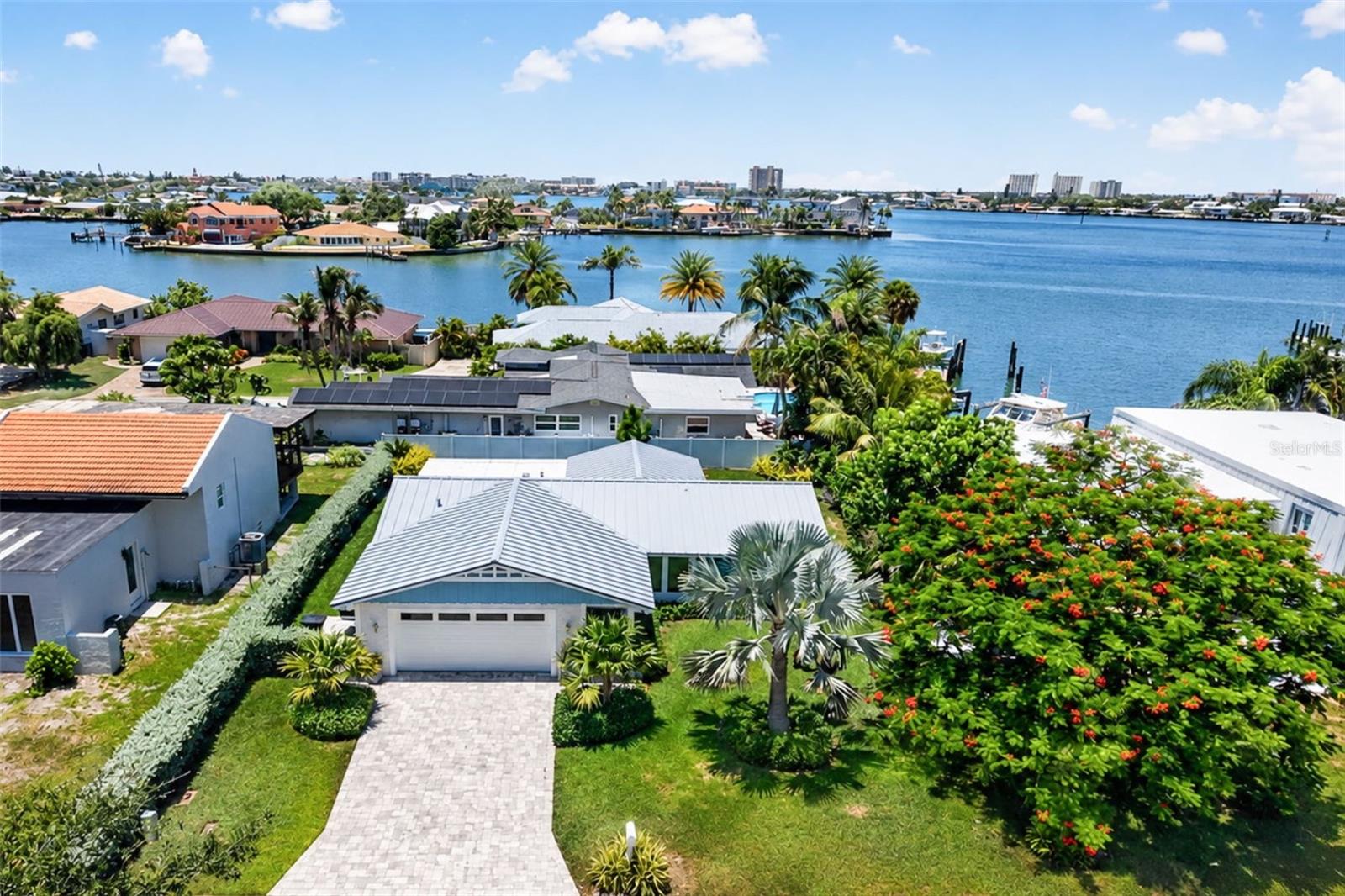 Virtually Staged. Perfectly positioned on one of Bahia Shores' most desirable streets, this professionally redesigned mid-century modern coastal residence blends timeless architecture, refined finishes, and an exceptional St. Pete Beach lifestyle just blocks from award-winning Gulf beaches, Corey Avenue, waterfront dining, boutique shopping, parks, and marinas. Featured on ABC and Hulu Live, the home was reimagined by a published interior designer in collaboration with a published contractor whose work has appeared in Florida Design and Architectural Digest, resulting in a residence where exceptional craftsmanship and thoughtful design are evident throughout. Filled with natural light, the open-concept floor plan showcases beautifully polished terrazzo floors and a custom kitchen featuring handcrafted wood cabinetry, quartz countertops, premium stainless steel appliances, and generous entertaining space, while custom millwork and spa-inspired bathrooms elevate the home beyond a typical renovation. The thoughtfully designed split-bedroom layout provides privacy for owners and guests, and the spacious Florida room, complete with two custom wardrobes, easily functions as a third bedroom, home office, fitness room, media room, or additional living space. The primary suite features linen-weave porcelain tile, Kohler fixtures, and a Toto bidet, while the guest bath offers a Calacatta Gold tiled walk-in shower, Kohler fixtures, and its own Toto bidet. Extensively renovated for beauty and peace of mind, the home also features a standing seam metal roof, hurricane impact-rated energy-efficient windows, custom cabinetry, decorative concrete paver driveway and rear patio, an epoxy-coated two-car garage, and numerous hurricane mitigation upgrades. Outside, exceptional tropical landscaping creates a lush, private setting around the covered paver patio, offering the perfect space for morning coffee, outdoor dining, or relaxing after a day at the beach. Whether walking to the Gulf, biking to Corey Avenue, taking a golf cart to dinner, or enjoying the nearby waterfront, parks, and marinas, this home delivers the effortless coastal lifestyle that makes Bahia Shores one of St. Pete Beach's most coveted neighborhoods. Ideal as a full-time residence, seasonal retreat, or sophisticated second home, this meticulously curated property offers the luxury of spending less time maintaining and more time enjoying the Gulf Coast, delivering a waterfront lifestyle without the waterfront price tag.