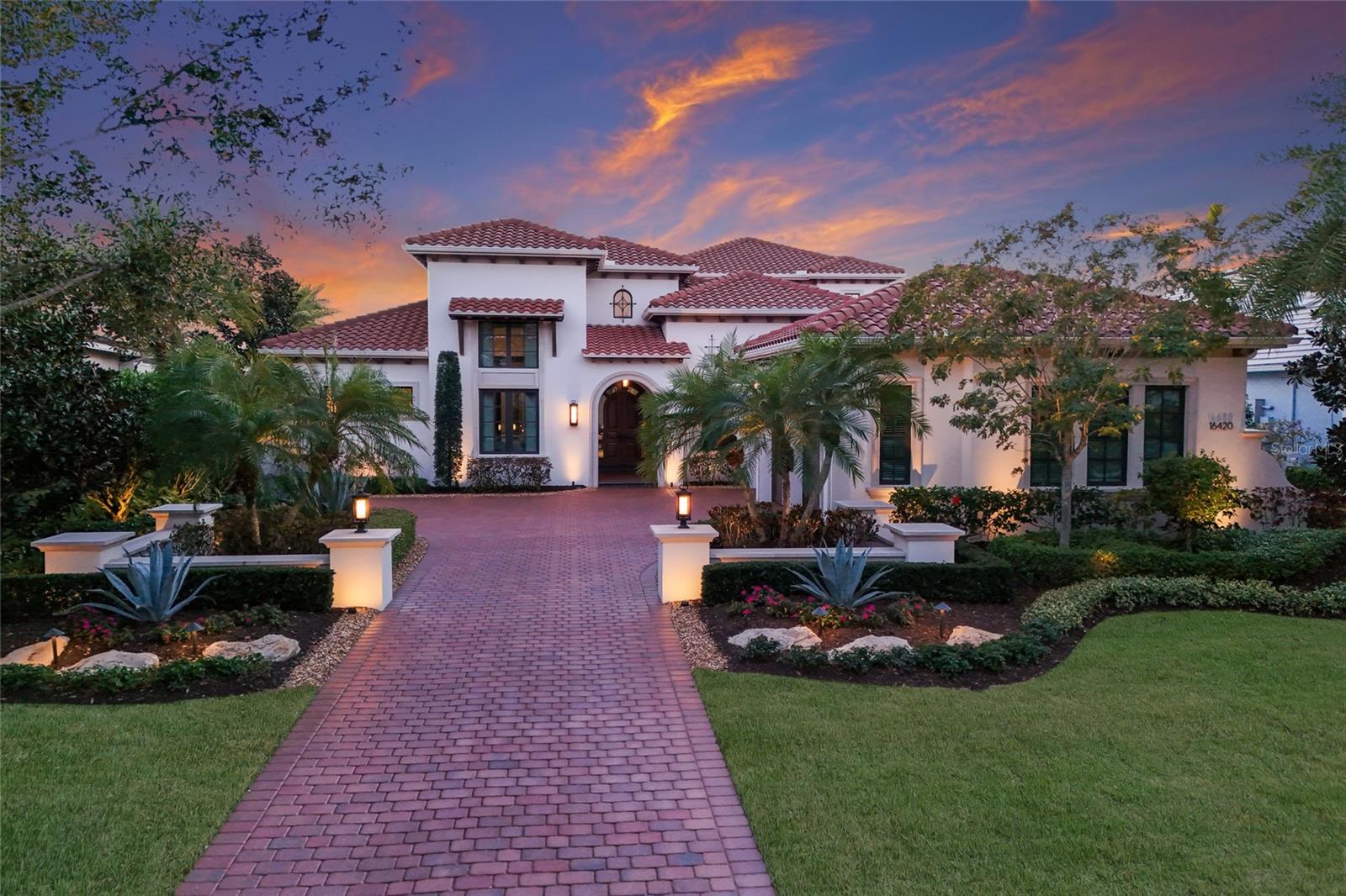 Situated behind the gates of The Lake Club in The Vineyards at Lakewood Ranch, experience refined lakefront living in this extraordinary custom-built Arthur Rutenberg estate, originally crafted as the model home and designed to exemplify the highest level of luxury, architectural detail, and craftsmanship. Being sold furnished, this remarkable residence offers a true opportunity to step immediately into an elevated waterfront lifestyle.
Impact-rated doors and windows invite natural light throughout while framing breathtaking lake views from nearly every vantage point. The outdoor living experience rivals a private resort, featuring a heated saltwater pool and spa overlooking the shimmering water. Endless entertaining awaits with a fully equipped outdoor kitchen, covered dining and lounge areas, and a stunning outdoor fireplace—all perfectly positioned to capture serene sunsets across the lake.
Inside, the expansive club room seamlessly pockets open to the outdoor space, creating effortless indoor-outdoor flow. Designed for unforgettable gatherings, it features a full bar, card table area, and is situated near the beautifully appointed wine room, offering both sophistication and warmth. The chef’s kitchen is equally impressive, boasting oversized counter space, top-of-the-line appliances, Sub-Zero refrigerator, Bosch dishwasher, Wolf Double Oven Stove, solid custom cabinetry, and a hidden walk-in pantry that blends functionality with refined design.
The primary suite is a private oasis, generously sized and thoughtfully positioned to capture tranquil water views. Dual walk-in closets, double vanities, and a spa-inspired bath with an oversized rainfall shower and soaking tub create a retreat-like atmosphere of comfort and indulgence. The first floor also offers a private guest suite with en-suite bath and walk-in closet, a dedicated office with soaring ceilings and ample space for any lifestyle needs, a convenient half bath for guests, and abundant storage throughout.
Upstairs, a spacious loft with built-in cabinetry, microwave, and mini refrigerator provides added comfort for family and guests. Step onto the newly updated second-floor balcony to take in panoramic views of the sparkling lake. Two oversized upstairs bedrooms, each with walk-in closets, en-suite bathrooms, and stunning water views, complete the upper level.
This exceptional residence is equipped with a whole-house generator, three brand-new 2025 A/C systems along with a mini-split system in the three-car garage, which also features custom cabinetry and storage for added convenience.  Every element of this home has been thoughtfully curated to capture timeless elegance, modern comfort, engineered hardwood flooring throughout and effortless entertaining in a premier waterfront setting.
A rare opportunity to experience elevated luxury living with The Lake Club at Lakewood Ranch, which privacy, sophistication, and lifestyle converge.
Enjoy the community outdoor amenities with resort-style and lap pools, tennis and pickleball courts, scenic parks, walking paths, and beautifully maintained green spaces designed for both recreation and relaxation.  Residents also enjoy dog parks, playgrounds, fitness center, indoor-outdoor bar venues, providing residents with refined yet relaxed gathering spaces for lunch, dinner and social events overlooking beautifully landscaped grounds and lakes.