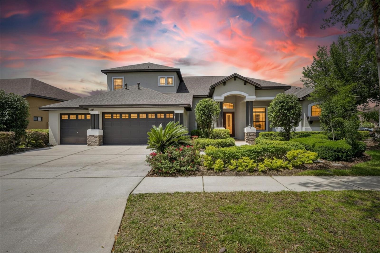 One or more photo(s) has been virtually staged. If you need a really BIG house zoned for one of the top high schools in the county, look no further! Welcome home to 107 Falling Water Drive—with 5 bedrooms and 5 baths, this is a truly magnificent residence offering the best in multi-generational living. With over 5,000 square feet of thoughtfully designed space, this former model home showcases countless upgrades on a beautifully landscaped corner lot. From the moment you step into the grand foyer and formal dining area, you’ll be captivated by the natural light and elegant engineered hardwood flooring that flow throughout the home. A designated office with French doors provides the perfect space for remote work, while a cozy den featuring floor-to-ceiling bookshelves overlooks the expansive pool deck, creating a serene retreat for relaxation or reading. The home’s layout is designed with privacy in mind, with the luxurious master suite tucked away on one side and a guest suite area with two bedrooms and a shared full bath on the opposite side. The primary suite is truly grand, offering a spacious sitting area, tray ceilings, and direct access to the pool. The en suite bath feels like a private spa, complete with dual sinks, an indulgent walk-through shower with three shower heads, and a soothing garden tub. For the culinary enthusiast, the chef’s kitchen is a dream come true—featuring high-end stainless steel appliances including a six-burner natural gas range with double ovens, a sleek stainless hood, granite countertops, 42-inch upper cabinets with under-cabinet lighting, a walk-in pantry, and a large island with ample storage and outlets. The kitchen seamlessly opens to a bright breakfast nook and an inviting family room, both overlooking the sparkling pool and backyard. Upstairs, you’ll find a fully equipped theater room with an 80” x 45” screen, a new built-in projector, and comfortable theater seating—all included with the home. Two additional bedrooms and a spacious flex room provide endless possibilities for a playroom, exercise area, or creative studio. Step outside to your personal paradise on the tiered pool and patio area, complete with multiple seating spaces, a mounted television, and a beautiful lighted waterfall feature surrounded by travertine tile under a screened enclosure. The outdoor kitchen is fully equipped with a gas grill, mini fridge, sink, countertop space, and under-counter storage—perfect for entertaining or poolside dining. Additional features include a large laundry room with built-in cabinetry, a 3 car garage with EV charger and an air-conditioned hobby room, a built-in bar with wine refrigerator, and stereo surround sound throughout the entire home. Seller just installed two brand NEW Carrier AC units! Centrally located near shops, restaurants, the Crosstown Expressway, and I-75, the gated community of Stonewood offers large lots and outstanding curb appeal. This home truly has it all—luxury, comfort, and functionality. You won’t find another home with this square footage and level of detail at this price. Schedule your private showing today!