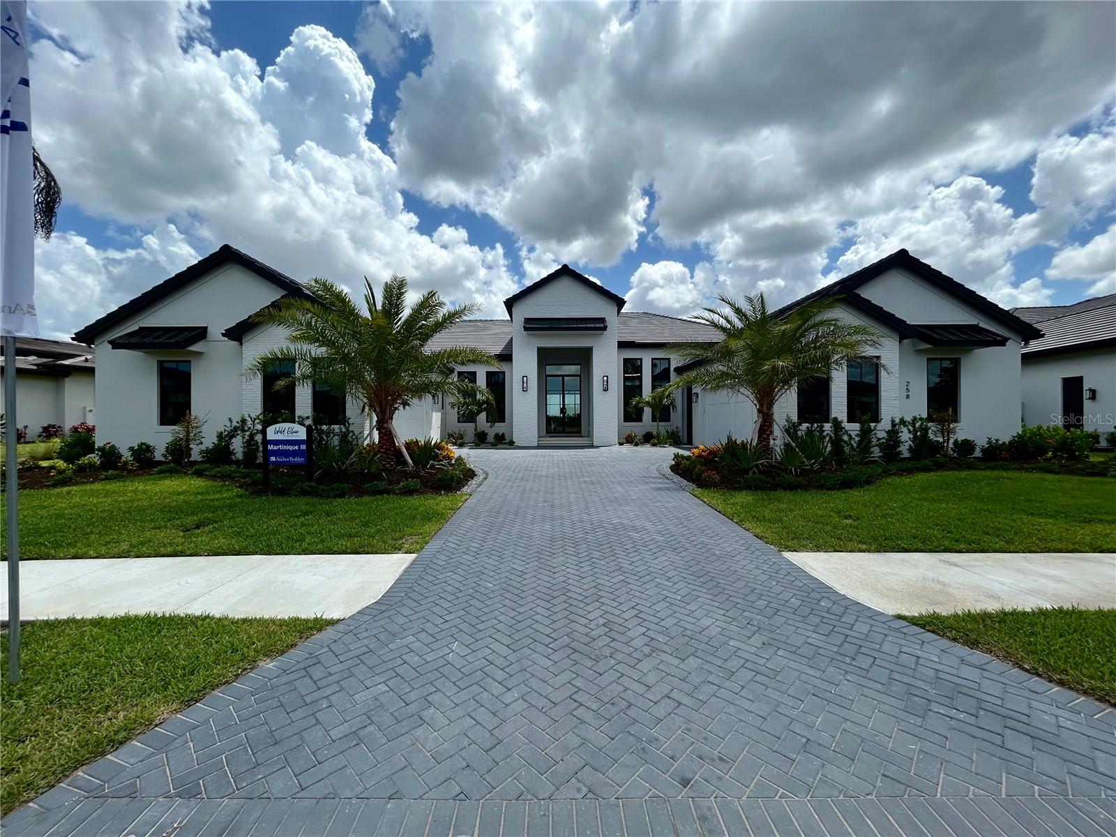 Renowned Sarasota custom home builder Roy Dupuis' Anchor Builders is pleased to introduce their newest model, The Martinique III in Wild Blue at Waterside.  This timeless and elegant modern farmhouse interpretation presents on a ½ acre Lapis water view homesite.  The wide homesite provided builder Roy Dupuis and celebrated residential designer Paul Fletcher the opportunity to create a home that truly maximizes both the extraordinary water and nature preserve views.

The welcoming grand approach to this one-of-a-kind residence is highlighted by towering columns adorned with white authentic brick and a wide and spacious auto-court embellished with exotic palms, for ease of ingress and egress into the opposing, generously sized 4-car garages.  

As you progress through the stunning entry doors and into the white brick arched grand foyer, your sense of arrival is accentuated by a feeling of calmness, comfort and a relaxed sense of tranquility that greets and invites you further into the home.

Vaulted ceilings graced with stained wood beams that connect the well-appointed Chef's Kitchen with an adjacent Pantry Kitchen welcome an abundance of natural light conveying a feeling of open and airy grandeur. The dining area is seamlessly connected to the grand room with its own subtle ceiling detail to define the space.  Custom cabinetry and countertops that feature wine and beverage centers function perfectly for eloquent, intimate "on the view" dining. 

Chevron pattern light Oak wood flooring and wide Galleries connect and entice you into each room where soothing blends of elegant warm and comforting colors, textures and furnishings are experienced.  The Primary Suite, complete with its own separate sanctuary space, hers and his closets and a spa like Primary Bath define the private side of the home.  Across the Gallery, the Study, and three ensuite Guest Bedrooms, Flex Room and Powder Bath, Utility and climate-controlled Storage area are found.  Step out into the generously appointed Outdoor Living-Dining-Pool area that blends seamlessly with the indoor spaces featuring an Outdoor Kitchen, Fireplace and Fire Pit for elevated Florida outdoor living.

From within the community, you can stroll, golfcart, bike to the planned Wild Blue at Waterside Clubhouse which will provide residents with fine and casual dining, social events and a well-appointed fitness center, classes, personal training, golf simulator, movie theatre and more. The shared Midway Sports Center includes 13 acres for neighbors to explore, play and connect. Miles of lakeside and preserve walking paths and trails, 6 tennis courts, 8 pickleball courts, sports pro shop, kayak launch, playground and of course, 2 dog parks for our fury friends ... All created for your next chapter nature-centric, active lifestyle! Interior Design and Furnishings by Carrie Riley of Riley Interior Design. 

Pricing  includes all Furnishings, TV’s, Artwork and Accessories and is net of a leaseback. See builder rep for details.