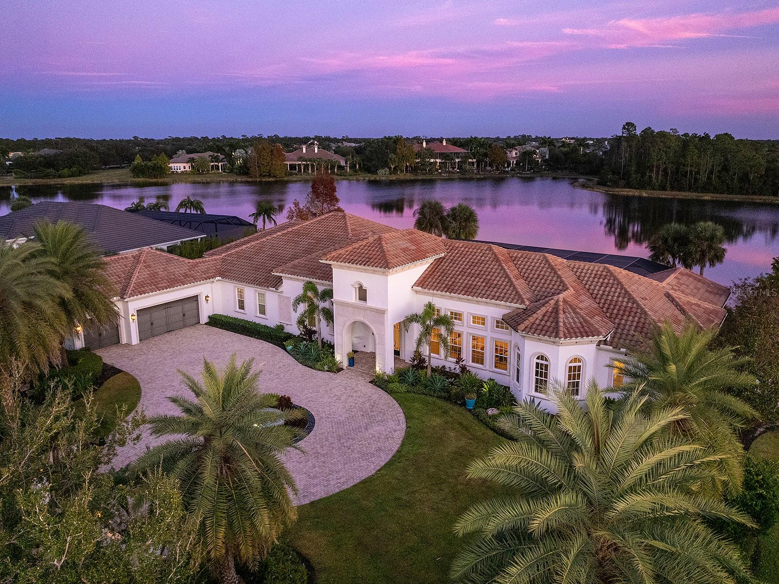 Poised to capture sweeping southeast-facing lake views, this impeccably designed Arthur Rutenberg residence presents a refined interpretation of indoor-outdoor living within the prestigious Concession community. Thoughtfully sited amid lush landscaping, the home blends architectural elegance with everyday comfort, creating an atmosphere that feels both elevated and effortless from the moment you arrive. Iron-and-glass double doors open to a luminous interior where coffered ceilings, polished travertine floors, and expansive pocketing sliders draw the eye outward to the pool and long water views beyond. The great room is both dramatic and inviting, offering generous space for entertaining while maintaining a natural connection to the outdoors. Anchoring the home, the gourmet kitchen is as functional as it is striking, featuring custom cabinetry with under- and over-cabinet lighting, a substantial floating island, quartz countertops, a discreet walk-in pantry, a Wolf gas cooktop, a beverage cooler, and premium stainless-steel appliances. Just beyond, the formal dining room and adjoining bar provide an elegant setting for elevated gatherings and intimate dinners alike. A private office offers a refined workspace. A versatile, spacious bonus room makes the perfect theatre room, golf simulator, or fitness area overlooking the lake, creating an inspiring backdrop for an elevated lifestyle. Three generously sized guest suites are thoughtfully positioned to ensure privacy, separate from the serene owner’s retreat. The primary suite serves as a true sanctuary, complete with a sitting area, expansive walk-in closets, and a spa-inspired bath with dual vanities, a soaking tub, and a walk-in shower. Outdoors, the expansive lanai becomes a natural extension of the living space, finished with travertine pavers, a fully equipped outdoor kitchen, and a resort-style saltwater pool (12'x61') and spa with sun shelf and fountains, all overlooking the tranquil lake. Whether hosting guests or enjoying a quiet evening at home, the setting offers a sense of everyday escape. The home has been thoughtfully enhanced with a suite of recent upgrades focused on comfort, efficiency, and peace of mind, including new air-conditioning systems, a whole-house generator, upgraded security with Ring doorbell, a Culligan reverse osmosis kitchen system, and a designer sound system. Outdoor enhancements include double-sealed travertine, a new patio cage, electric hurricane shades, accent lighting, wiring for an outdoor television, refreshed landscaping, and updated irrigation with front landscape lighting. Additional improvements include new flooring in a guest bedroom, upgraded electrical in select rooms, garage ceiling storage racks, and added utility connections. New carpet to be installed in 2026. The Concession, home to the PGA Tour World Golf Championship and Senior PGA Championship is one of the most prestigious golf communities in the country and provides a serene environment.