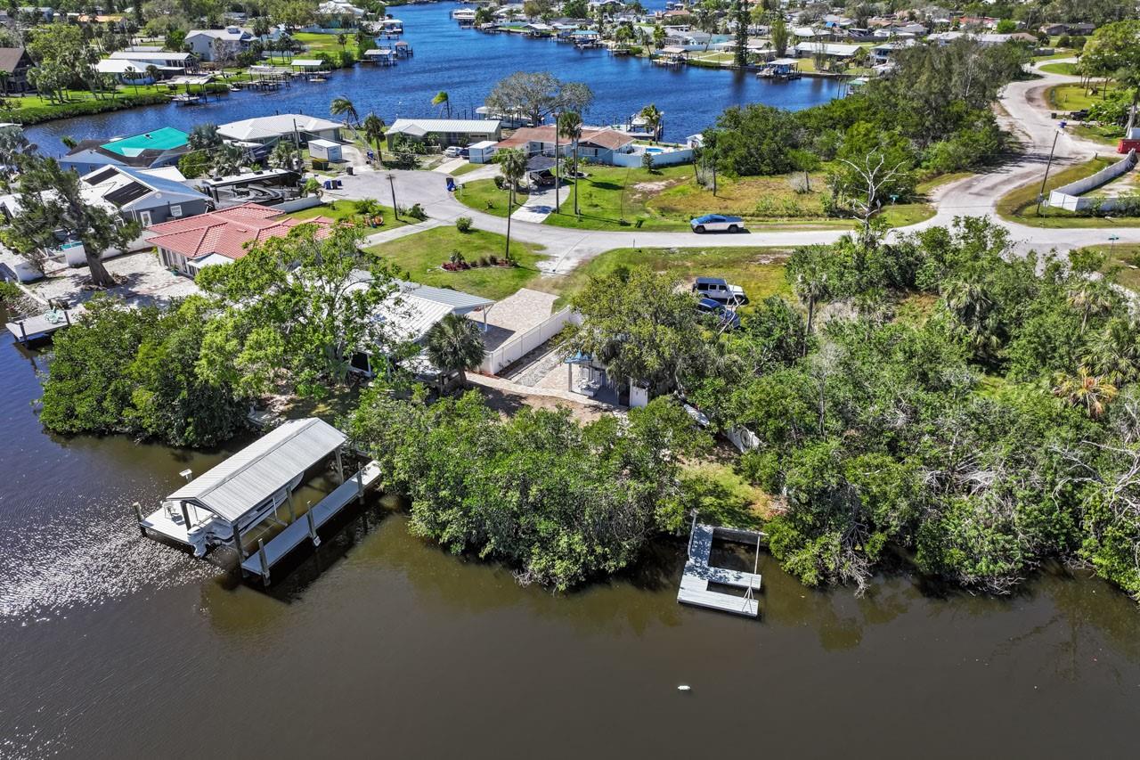 Completely remodeled WATERFRONT home with 2 bedrooms, 2 bathrooms, and a 1-car carport located on the beautiful Ruskin Inlet with NO HOA/CDD now for sale! This is a dream property for any boating or fishing enthusiast. Plenty of space on the lot to park your trailer or motor home - even comes with 50-amp service! METAL ROOF (2017), NEWER hot water heater (2024), fenced, OUTDOOR KITCHEN, paver parking area, reinforced seawall with added seawall cap, DOCK with COVERED BOAT LIFT, shed, outdoor shower, FIRE PIT, floating kayak dock, and a COVERED SCREENED LANAI with NEW FLOORING. Inside, you'll find LUXURY VINYL FLOORING, TILE FLOORING in the style of wood plank, recessed lighting, QUARTZ COUNTERTOPS, and all NEWER APPLIANCES! There's a large Great Room housing both the living room area and kitchen, with STAINLESS STEEL appliances, a beautiful ISLAND with room for prep & seating, SOFT-CLOSE cabinets all the way up to the ceiling for maximum storage, pendant lights, and a lovely backsplash adding the finishing touch to this wonderful gathering space. The Laundry Room is separated by a barn-style door and features NEWER GE Profile washer/dryer, along with built-in shelving and storage! The Primary Bedroom includes a WALK-IN CLOSET and EN-SUITE BATHROOM complete with an updated single sink vanity, shower stall with built-in bench, and water closet. The spacious secondary bedroom is conveniently positioned across from the second full bath, which has an updated single sink vanity, tub/shower combination, and is tastefully decorated with a gorgeous textured wallpaper, chair rail, and wainscoting. Conveniently located with easy access to US-41 and I-75, this home offers the tranquility of waterfront living while remaining close to Tampa, St. Petersburg, Bradenton, and surrounding areas.