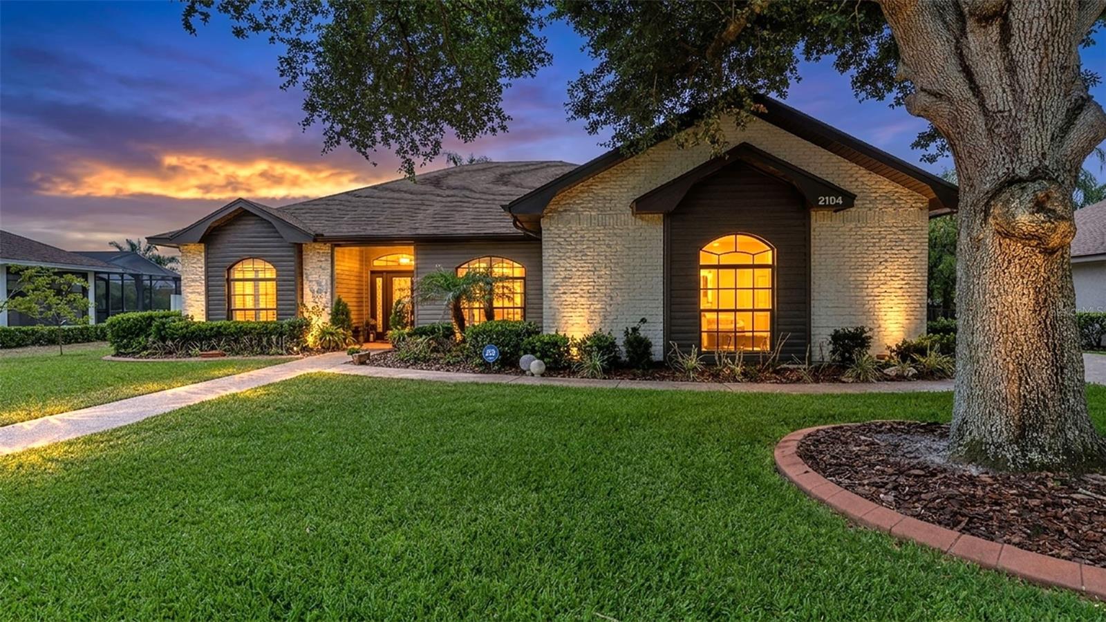 Experience the perfect blend of quality craftsmanship, thoughtful design, and modern updates in this custom-built 3-bedroom, 2-bathroom home with a dedicated office, dining room, and over a quarter-acre of beautifully landscaped property in desirable Bloomfield Hills. Built by legendary local builder Ernie White, this home showcases the attention to detail and superior construction that made his work so highly sought after. Recently refreshed by a professional interior decorator, the home features stylish accent walls, decorative lighting, and designer touches throughout. The open-concept layout, soaring ceilings, abundant natural light, ceiling fans, and a harmonious mix of wood, tile, and carpet flooring create a natural and inviting atmosphere. The spacious kitchen is designed for both function and style, offering stainless steel appliances, a striking tile backsplash, abundant custom cabinetry, and generous high-end laminate countertop space. The living room features a modern propane gas fireplace, as well as two sets of doors leading to the outdoor deck, seamlessly connecting indoor and outdoor living. The luxurious primary suite is a private retreat with dual walk-in closets, a spa-like en suite bathroom featuring a garden tub, tiled walk-in shower, dual vanities and sinks, an additional bathroom closet, and a private water closet. Located on the opposite wing, two additional bedrooms provide comfort and privacy, while the second full bathroom offers dual sinks, a shower/tub combination, and direct access to the patio and deck. Additional highlights include a separate laundry room, a dedicated office with custom built-in shelving, and a stunning enclosed Florida room filled with natural light and overlooking the backyard, complete with its own exterior access. Outside, enjoy a thoughtfully landscaped yard with mature trees, fruit-bearing plants, irrigation system, outdoor lighting, and a spacious deck perfect for entertaining. A side-entry two-car garage adds curb appeal and convenience. Recent improvements include a new tankless water heater (2025), HVAC system (2021), and roof replacement (2022). Residents of Bloomfield Hills enjoy amenities including sidewalks and a tennis court, all while being conveniently located in North Lakeland just minutes from Publix, Walmart, Lakeland Square Mall, shopping, dining, and with easy access to both US-98 and I-4 for travel throughout Central Florida.