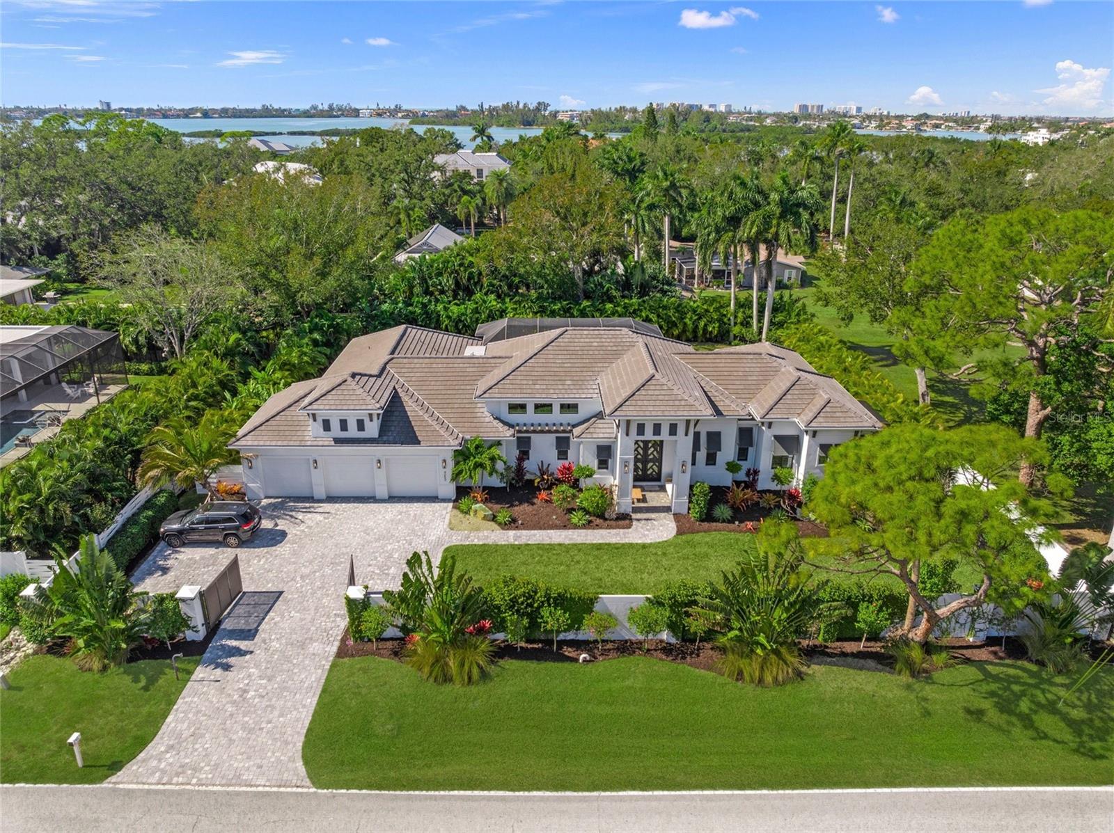 A private, resort-caliber residence where exceptional architectural execution, bespoke finishes, and seamless indoor-outdoor living define the experience. Located in Sarasota’s coveted Oyster Bay enclave, this custom-built home features a private gated entry and is surrounded by extensively upgraded, professionally curated tropical landscaping that creates a strong sense of arrival and privacy.

Inside, soaring 16-foot ceilings, clerestory windows, and expansive walls of glass flood the home with natural light while highlighting clean architectural lines and premium finishes throughout. Pocketing sliders open effortlessly to outdoor living spaces, creating true indoor-outdoor integration. Wide-plank Duchateau French Oak flooring provides warmth and timeless sophistication across the residence. The open-concept great room is designed for both large-scale entertaining and refined everyday living.

The chef’s kitchen rivals those found in luxury hospitality settings, featuring custom shaker cabinetry, honed quartz and quartzite surfaces, an oversized statement island, premium Monogram appliances, and a walk-in pantry designed for both functionality and elegant storage. A Culligan whole-house water filtration system with reverse osmosis serves the kitchen and supports a wellness-focused lifestyle.

The primary suite serves as a private retreat, highlighted by custom millwork, designer lighting, a spa-inspired bath with freestanding soaking tub, expansive glass-enclosed shower, bespoke closet build-outs, and a private enclosed outdoor shower with open sky and tropical views. Each additional bedroom includes a private en-suite bath, providing exceptional comfort and privacy for family and guests.

Outdoor living is elevated by an expansive covered lanai centered around a heated saltwater pool and spa, outdoor kitchen, and multiple lounge areas surrounded by lush, mature landscaping. Raised irrigated garden beds provide space for herbs and seasonal produce, while established banana trees and maturing mango and guava trees enhance the property’s tropical estate feel. A generous, gated front yard offers an additional secure and private outdoor living area.

Additional features include advanced Lutron smart-home automation, integrated audio, lighting, and security systems, impact-rated windows and doors, whole-house generator, gas-heated pool and spa, gas firepit, Icynene spray foam insulation, irrigation well, EV charging capability, and a spacious three-car garage with high ceilings, epoxy flooring, and abundant storage.

Ideally located just blocks from Siesta Key’s north bridge, Publix, Trader Joe’s, CVS, and Walgreens, with walking access to family friendly Red Rock Park in this quiet neighborhood with no major through streets.

4050 Camino Real represents a rare offering that combines superior construction quality, elevated design, and an exceptional Sarasota location.