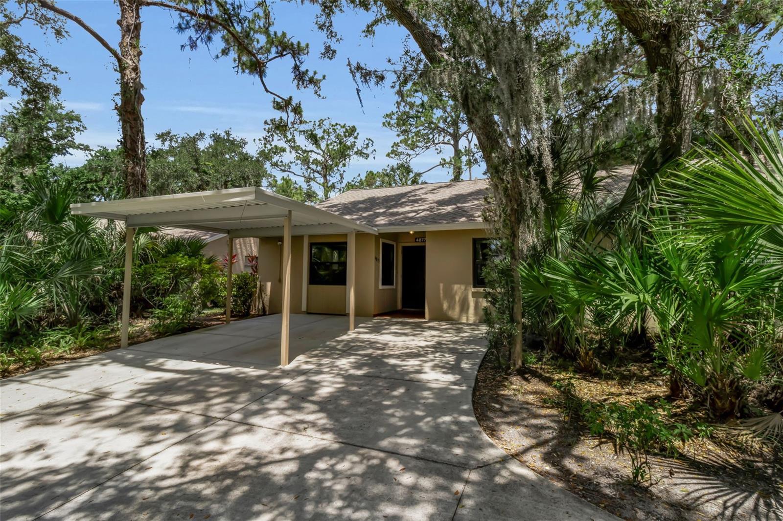 Virtually Staged. Welcome to easy Sarasota living in the desirable Village Gardens community! This beautifully maintained two-bedroom, two-bath villa offers a combination of comfort, convenience and low-maintenance living in an unbeatable location. Go inside to discover soaring ceilings, abundant natural light, fresh interior paint, and new plush carpeting that create a bright and inviting atmosphere throughout. The spacious floor plan features an open living and dining area, while the in-unit washer and dryer provide everyday convenience. Enjoy your morning coffee or unwind in the evening on the covered and screened lanai, surrounded by lush, mature landscaping that enhances the peaceful setting. Hurricane-impact windows, with exception of the sliding glass doors, provide added protection and peace of mind, while your private covered carport offers convenient parking near your front door. Village Gardens residents enjoy an active lifestyle with exceptional amenities including a community pool, clubhouse, tennis and pickleball courts, and bocce ball. Best of all, exterior landscaping maintenance is included in the HOA fee, allowing you to spend more time enjoying everything Sarasota has to offer. Ideally just minutes from SRQ Airport, Ringling College of Art & Design, Indian Beach, downtown Sarasota, and the University Town Center (UTC) shopping and dining district, this villa places world-class beaches, cultural attractions, restaurants and entertainment within easy reach. Whether you're seeking a year-round residence, seasonal retreat or investment opportunity, this move-in ready villa is must-see. Schedule your private showing today and experience the charm and convenience of Village Gardens for yourself.