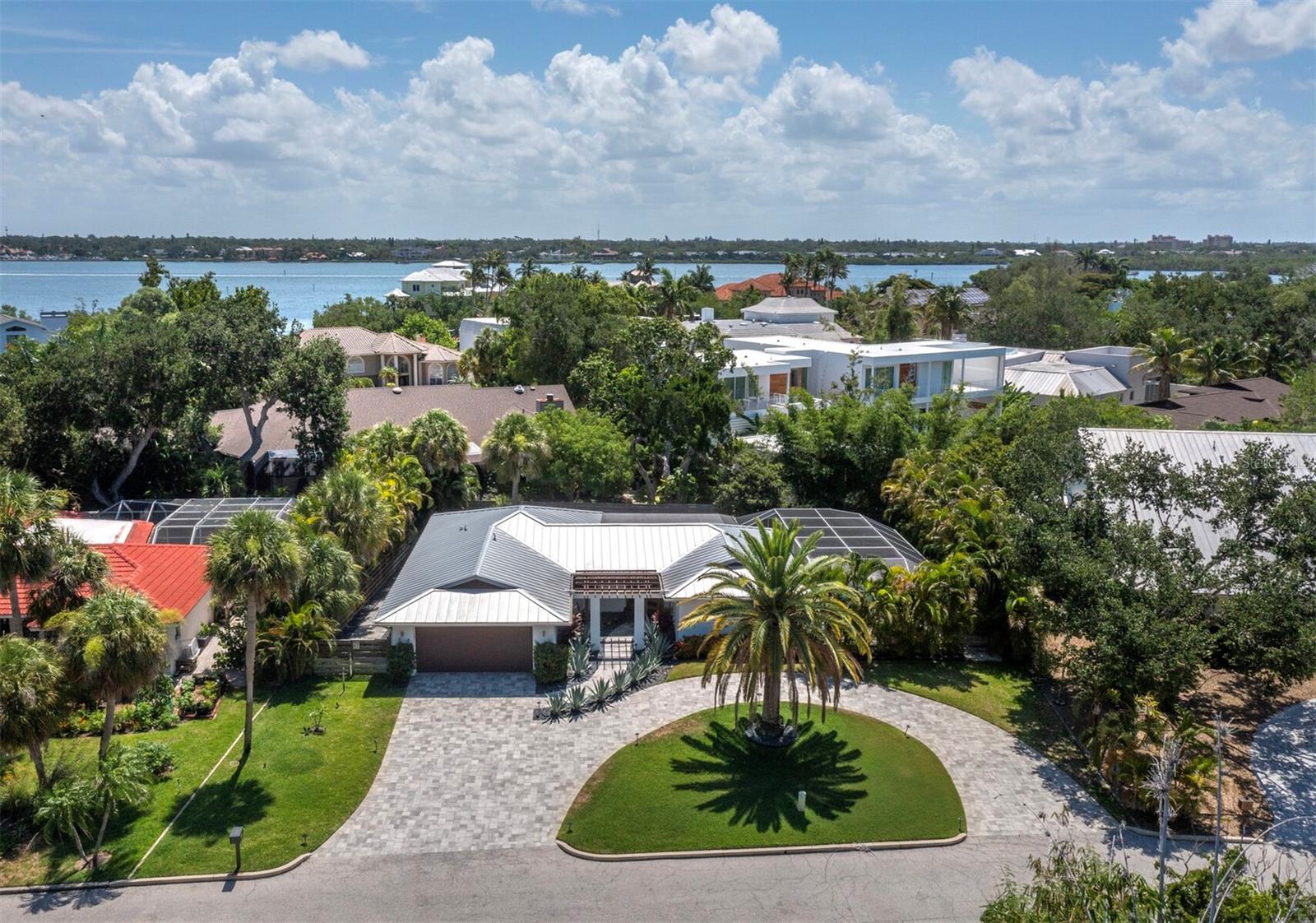 Beautifully reimagined and thoughtfully updated, this modern coastal residence on Siesta Key offers the relaxed island lifestyle so many buyers are seeking, with a wonderful blend of style, comfort, and low-maintenance living. Set on an oversized lot in a peaceful neighborhood near the world-famous white quartz sands of Siesta Beach and the charm of Siesta Village, this move-in-ready home feels private, inviting, and easy to enjoy. A handsome approach with tropical landscaping, a large circular driveway, and a Brazilian wood pergola creates a welcoming first impression. Contemporary wood-and-glass entry doors open to a light-filled interior where hand-scraped wood floors, clean architectural lines, and warm designer details give the home a fresh, sophisticated feel. The open great room, dining area, and custom kitchen flow beautifully together for everyday living and effortless entertaining, with illuminated tray ceilings, striking wood beam accents, and a stunning kitchen featuring custom cabinetry, Calcutta quartz countertops, herringbone backsplash, stainless Viking appliances, pendant lighting, and an oversized waterfall-edge island with shiplap detail and generous seating. Recent enhancements include a new built-in pantry, an elegant dining chandelier, and a family room with a new electric fireplace and custom built-ins, creating a comfortable gathering space for quiet evenings or casual entertaining. The thoughtful floor plan includes three spacious bedrooms and two beautifully appointed baths with custom tilework and carefully selected finishes. Outdoors, lush tropical landscaping creates a private, Zen-like setting around the screened lanai and freeform pool. Begin your day with coffee on the pool deck while enjoying brilliant sunrises and end the evening with Siesta Key’s vibrant sunsets just minutes away at nearby Siesta Beach. The backyard has also been updated with no-maintenance faux grass for an attractive, easy-care outdoor space. Additional features include impact windows and sliding doors, a metal roof, and generous parking. Ideally located near Siesta Key’s renowned beaches, the boutiques and dining of Siesta Village, and vibrant downtown Sarasota’s cultural amenities just 15 minutes away, this stylish island residence is ready to be enjoyed.