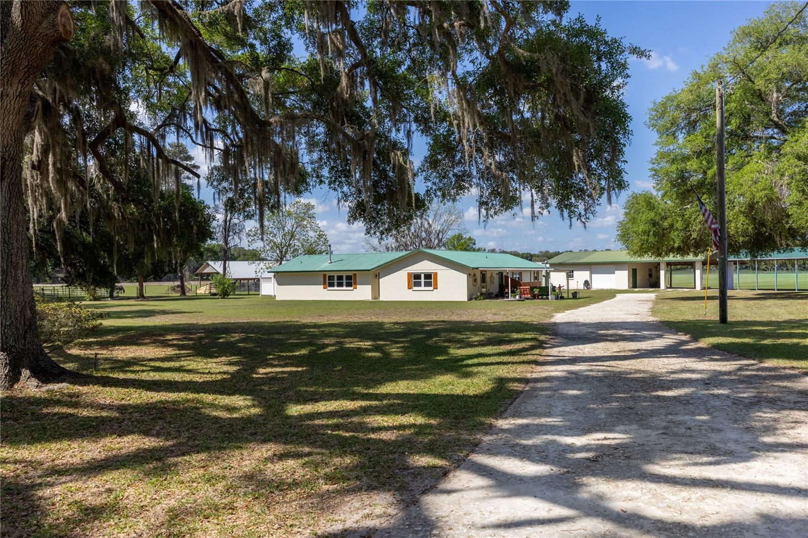 Welcome to a truly exceptional opportunity to own a breathtaking 20-acre ranch in highly sought-after Gilchrist County—where refined comfort, thoughtful design, and peaceful country living come together in perfect harmony. Privately tucked just off a paved road behind a gated entrance, this remarkable property unfolds with sweeping pasture views, majestic mature oaks, and a gentle, year-round breeze that captures the very essence of North Florida living. The fully renovated solid block home has been meticulously maintained and beautifully upgraded, blending rustic ranch charm with elevated, high-end finishes. Designed for both everyday living and effortless entertaining, the spacious split floor plan offers four bedrooms and two bathrooms, complemented by two inviting living areas—one centered around a cozy fireplace, perfect for relaxing evenings at home. Natural light pours in through new windows, highlighting the warmth and character throughout.

At the heart of the home, the stunning kitchen is both functional and eye-catching, featuring granite countertops, new appliances, and custom high-end cabinetry with pull-out drawers and unique, one-of-a-kind fixtures. A picturesque window above the sink frames serene views of the property, bringing the beauty of the outdoors right into your daily routine. The primary suite is a true retreat, complete with a dream walk-in closet fully customized with built-ins, shelving, and drawers for optimal organization. Step outside and experience what truly sets this property apart. Designed with the equestrian enthusiast or working farmer in mind, the pristine 60x48 horse barn features four oversized 12x28 stalls with flexibility to reconfigure, along with a well-designed wash station for ease and efficiency. The land is fully fenced with durable RAM fencing and thoughtfully divided into four paddocks, making it perfectly suited for horses or livestock.
Adding even more versatility, the enclosed concrete shop with an attached two-car carport provides a highly functional space—ideal for a workshop, storage, hobbies, or even a home-based business. Additional improvements include multiple outbuildings for gardening, a tack room, and equipment storage. A charming chicken coop—complete with resident chickens—adds to the authentic farmstead lifestyle, while mature pear and pecan trees provide both beauty and bounty. This is more than just a property—it’s a turnkey ranch lifestyle offering privacy, functionality, and endless possibilities, all in a location that keeps you conveniently connected while feeling worlds away.