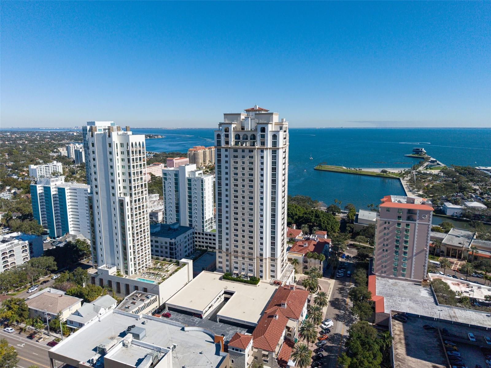 LUXURY LIVING WITH SWEEPING WATER AND CITY VIEWS IN THE HEART OF DOWNTOWN ST. PETERSBURG
Experience refined urban living at Parkshore Plaza, one of downtown St. Petersburg’s most distinguished luxury towers. This prestigious residence offers breathtaking, front-row views of Tampa Bay, the vibrant downtown skyline, and the surrounding waterfront parks that frame the city’s iconic landscape.
The expansive covered wraparound balcony, accessible from three separate interior points, serves as an extraordinary outdoor living space where the views stretch from east to west, creating a constantly evolving panorama of sparkling bay waters, passing boats, glowing sunsets, and the distant silhouette of the Sunshine Skyway Bridge. It is the perfect setting for morning coffee, evening cocktails, or simply taking in the beauty of St. Petersburg’s waterfront lifestyle.
Inside, this elegant 3-bedroom, 3.5-bath residence spans 2,767 square feet of thoughtfully designed living space, ideal for both everyday comfort and gracious entertaining.
Upon exiting the elevator, you are welcomed into your own private entry lobby, a coveted feature that enhances both privacy and security.
The interior showcases newly installed wood flooring, bringing warmth and sophistication to the home while complementing the timeless architectural finishes. The foyer opens into a spacious great room where walls of glass frame spectacular views of Tampa Bay and the surrounding parks.
Every window is appointed with either high-end white plantation shutters or adjustable mesh blinds, allowing natural light to fill the space while maintaining comfort and privacy.
The well-appointed kitchen blends functionality with style, featuring tropic brown granite countertops, a gas cooktop, smart refrigerator, rollout pantry shelving, abundant cabinetry, and recessed lighting. An inviting eat-in kitchen vestibule and convenient dry bar create additional space for hosting and entertaining.
The expansive primary suite provides a private retreat with two oversized walk-in closets and a spacious ensuite bath highlighted by dual granite-topped vanities and a large soaking tub. The additional bedrooms are equally well proportioned, including a second bedroom with its own generous walk-in closet.
This residence also includes two secure parking spaces, along with a large private storage unit.
Residents of Parkshore Plaza enjoy an exceptional suite of amenities, including 24-hour concierge service, on-site management, heated pool and spa, fitness center with massage room, billiards room, business center, library, and an elegant social room with full kitchen, bar, formal dining space, and private balcony. The building’s lavish fountains, marble finishes, and Mediterranean-inspired architecture create a sense of timeless grandeur throughout.
Perfectly positioned in the epicenter of downtown St. Petersburg, Parkshore Plaza places you just steps from waterfront parks, world-class dining, museums, theaters, boutiques, and the Pinellas Trail, a beloved 50-mile biking and walking path. With its vibrant arts culture, stunning waterfront, and walkable downtown lifestyle, St. Petersburg continues to be one of Florida’s most desirable places to call home.