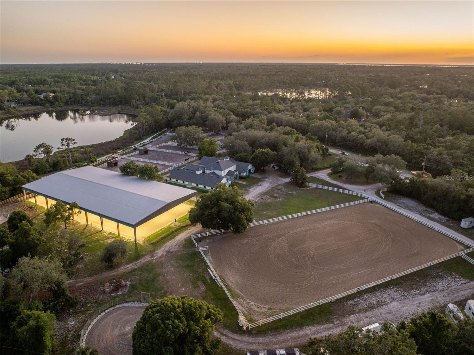 Tucked beneath majestic oak canopies and surrounded by the beauty of Old Florida, welcome to Silver Springs Equestrian,a rare opportunity to own an established, income-producing equestrian facility in the heart of Geneva. Situated on 10 gated acres with peaceful lake views and endless possibilities, this exceptional property blends functionality, charm, and true equestrian lifestyle living.  Designed as a full-service community equine facility, Silver Springs Equestrian offers boarding, training, lessons, trail rides, clinics, and space for both local riders and traveling equestrians alike. The grounds are thoughtfully laid out with 23 stalls between two wide aisle barns, 15 paddocks, multiple riding and training areas, and impressive infrastructure already in place for a thriving operation or private estate.  
Equestrian amenities include a 100’ x 200’ covered and lighted arena with upgraded footing, a 200’ x 400’ outdoor arena complete with jumps, standards, barrels, poles, and dressage setup, plus a 60’ round pen for training and exercise. Additional features include hot and cold water wash racks, grooming and tack-up bays, gated entry, extensive parking inside and outside the gate, and three 50-amp RV hookups with water service. Whether you envision a premier boarding and training facility, private horse farm, clinic destination, or family compound, this property is equipped to deliver.  The primary residence offers a unique and functional layout with living quarters thoughtfully integrated into the equestrian lifestyle. Upstairs features two bedrooms and a full bath, while the lower level includes an office, oversized tack room with sitting area, laundry room, and additional half bath. A separate 3 bedroom, 2 bath secondary residence provides ideal accommodations for guests, trainers, staff, rental income, or multi-generational living.  Perfectly positioned approximately 1.5 hours from the World Equestrian Center, under an hour to Orlando attractions, and within reach of Florida beaches, this one-of-a-kind Geneva equestrian estate combines peaceful country living with convenience and opportunity. From the sprawling oak-lined grounds to the fully equipped training facilities, Silver Springs Equestrian is more than a property.....it is a destination and lifestyle.
