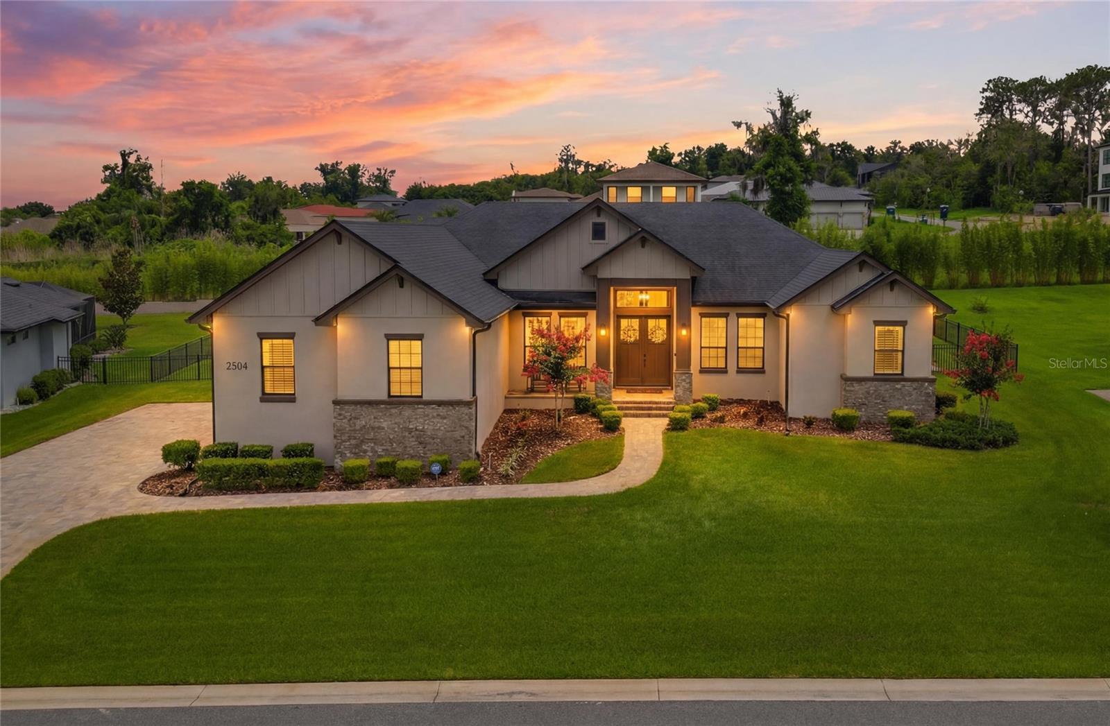 LUXURY, PRIVACY, AND EXCEPTIONAL CRAFTSMANSHIP converge in this stunning custom built estate located within one of South Lakeland’s most sought after gated communities, designed and built by Hulbert Homes. Perfectly situated on an expansive homesite, this meticulously designed 4 bedroom, 3 bath residence with an oversized 3 car garage offers the ideal blend of elegance, comfort, and modern functionality.

From the moment you arrive, the home’s striking contemporary farmhouse architecture, manicured landscaping, and inviting covered entry create an unforgettable first impression. Step through the double front doors into a grand foyer showcasing soaring ceilings, rich hardwood flooring, extensive crown molding, and designer finishes throughout.

The thoughtfully designed open-concept floor plan is centered around a breathtaking great room featuring a dramatic tray ceiling and oversized sliding glass doors that seamlessly blend indoor and outdoor living. The chef’s kitchen is truly the heart of the home and is appointed with custom cabinetry, premium stainless steel appliances, double wall ovens, a built-in wine refrigerator, oversized center island with seating, elegant quartz countertops, and an abundance of workspace and storage; perfect for both everyday living and entertaining.

The private owner’s retreat serves as a luxurious sanctuary, offering generous proportions and a spa-inspired bath complete with dual vanities, a freestanding soaking tub, and an oversized walk-in shower designed for ultimate relaxation.

A desirable split-bedroom layout provides privacy and comfort for family and guests, while a dedicated office/flex room offers endless possibilities as a home office, fitness room, or media space.

One of the home’s most impressive features is the expansive screened lanai, complete with a beautiful tongue and groove wood ceiling, outdoor television, wet bar, and multiple entertaining spaces that invite year round enjoyment of Florida’s outdoor lifestyle. Beyond the lanai, the sprawling backyard provides an incredible sense of space and privacy, with ample room to create the backyard oasis of your dreams.

Residents of this exclusive gated community enjoy the peace of mind that comes with privacy and security while being just minutes from South Lakeland’s premier shopping, dining, medical facilities, top rated schools, and convenient access to the Polk Parkway and I-4 corridor.

Opportunities to own a custom estate of this caliber on an oversized homesite in one of South Lakeland’s premier gated communities are exceptionally rare. This extraordinary residence offers luxury living at its finest and is ready to welcome its next