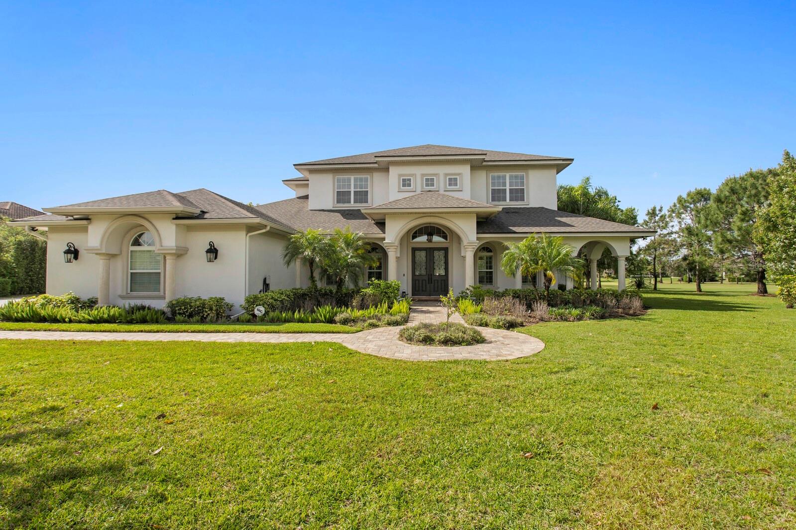 Welcome to Steeplechase, one of Odessa’s most exclusive gated communities. Located within a cul-de-sac in the heart of Steeplechase, this remarkable, recently remodeled, lakefront property seamlessly blends indoor and outdoor living with expansive entertaining spaces and cozy retreats. This estate sits on 2.87 acres of lush greenery, fruit and avocado trees, and a massive screened lanai. Inside the home, updated in 2023 with exquisite attention to details presented through, custom cabinetry, designer lighting, and engineered hardwood floors. Overlooking the inviting living room is the well-appointed kitchen, which is anchored by a large built-in seating nook that’s illuminated by a Kelly Wearstler light fixture. The appliance suite, which includes a double oven, refrigerator drawers, and paneled refrigerator, is perfectly complemented by the wood cabinetry and quartzite counters—and don’t miss the wine cellar, wet bar, and butler’s pantry. The main-floor primary suite is a quiet haven with direct lanai access and a spa-like ensuite bath. The owners suite bathroom comes equipped with a walk in shower & a stand-alone soaking tub. The additional bedrooms are located on the second floor, each includes a walk-in closet.The entertainment space on the second floor provides an additional loft space/bonus room with a wet bar and mini fridge. The second floor also provides a full movie theater and a projector screen. The second floor offers a study corner/reading nook and three additional bedrooms. Two of the bedrooms share a Jack-and-Jill full bathroom. On the opposite side of the second floor, you will find the third additional bedroom and full bathroom that provides a laundry chute from the second floor to the first floor laundry room. Step outside onto the second-story private balcony to enjoy the view of the pool and lake. Entertain with ease in the outdoor living space, which includes an outdoor kitchen, fireplace, and heated pool. Open up the sliding pocket doors to create a flowing open floor plan between indoor and outdoor living. Enjoy the serene lake views, swim some laps in the large saltwater pool, or just enjoy the peaceful surroundings. The oversized 3-car garage is already wired for EV charging and features epoxy floors and ample storage. Roof, interior and exterior paint 2023. The property is located 25 minutes from the Tampa International Airport, yet this home feels like a true oasis. Hop in your golf cart and enjoy a ride through this beautiful community to enjoy the ultimate Florida lifestyle. This is your opportunity to own a truly exceptional home within the gates of Steeplechase.