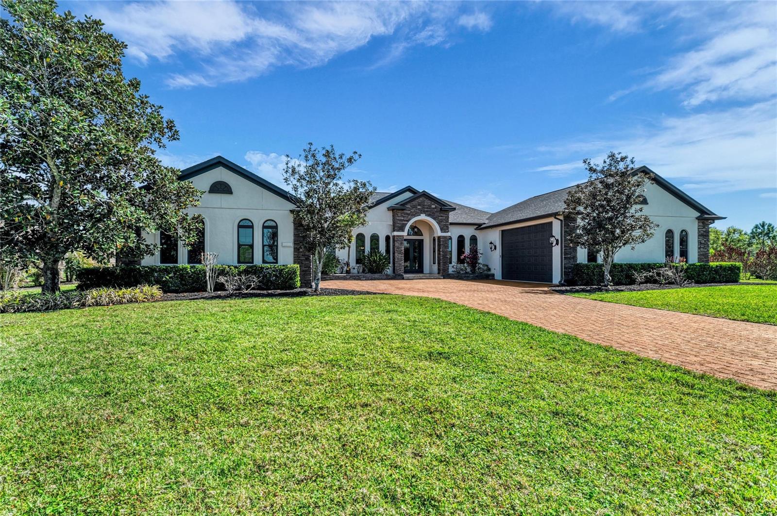 A sweeping, ultra-private 1.27-acre preserve estate matching resort-level wellness with absolute structural peace of mind. Fresh off a significant $150,000 price adjustment, this masterfully reimagined single-story residence is an achievement in refined Florida acreage living, boasting over $400,000 in recent premium upgrades and renovations. The home’s striking symmetry is anchored by two separate, oversized garages flanking a grand entrance and a sprawling brick pavered drive and auto court. Nestled on its private lot, every facet has been elevated—from the brand-new roof (2022) to the full PGT WinGuard impact glass envelope (2025) featuring 7700-series aluminum on the front elevation and high-efficiency 5500-series vinyl along the perimeter. Security and independence are paramount, highlighted by a discreet, climate-controlled structural vault, reinforced concrete walls throughout the home, and a new Guardian 26kW whole-home generator (2025) powered by a 1,000-gallon buried propane tank. The interior is a silent sanctuary featuring a nearly $40,000 HVAC overhaul (2024) with dual 18 SEER2 Trane XV18 variable-speed systems, hospital-grade Clean Effects filtration, and a sophisticated seven-zone, WIFI controlled climate array. The culinary core is equally formidable, centered by a chef’s kitchen featuring a professional Wolf range, dedicated Wok station, walk-in pantry, and dedicated wine refrigeration. This space flows seamlessly through impact sliders to a brand-new summer kitchen, fully equipped with a built-in premium grill, high-volume ventilation hood, and outdoor refrigeration for effortless poolside entertaining. The grand living room has 10-foot pocket sliders that truly maximize indoor/outdoor living and is pre-wired for a motorized projection screen, projector, and state-of-the-art sound system with indoor/outdoor speakers already built in. Designed for wellness and multi-generational living, the single-story layout features two primary suites at the rear of the home, each providing direct access to a resort-style heated pool and jacuzzi spa. The professional gym is uniquely positioned within a dedicated annex off the executive library, also accessible via the primary owner's EnSuite. Additionally, the master EnSuite leads to its own private, walled screen-top enclosure—a secluded, open-air annex housing an infrared sauna with direct access to the pool and spa. The versatile garage bays offer oversized clearance specifically engineered to easily accommodate Class B and Class C Sprinter luxury adventure vans or car lifts, while the whole-house reverse osmosis system ensures bottled-quality water at every tap. From the impenetrable structural envelope to the self-sustaining utility core, every detail has been meticulously engineered so you can effortlessly enjoy everything an acreage lifestyle offers. This isn’t just a place to live—it is a private, everyday resort designed for making unforgettable memories, hosting epic gatherings, and enjoying total peace of mind for generations to come. A property of this caliber must be viewed in person to appreciate the sheer scale of its thoughtful design and craftsmanship; schedule your private tour today to discover it all!